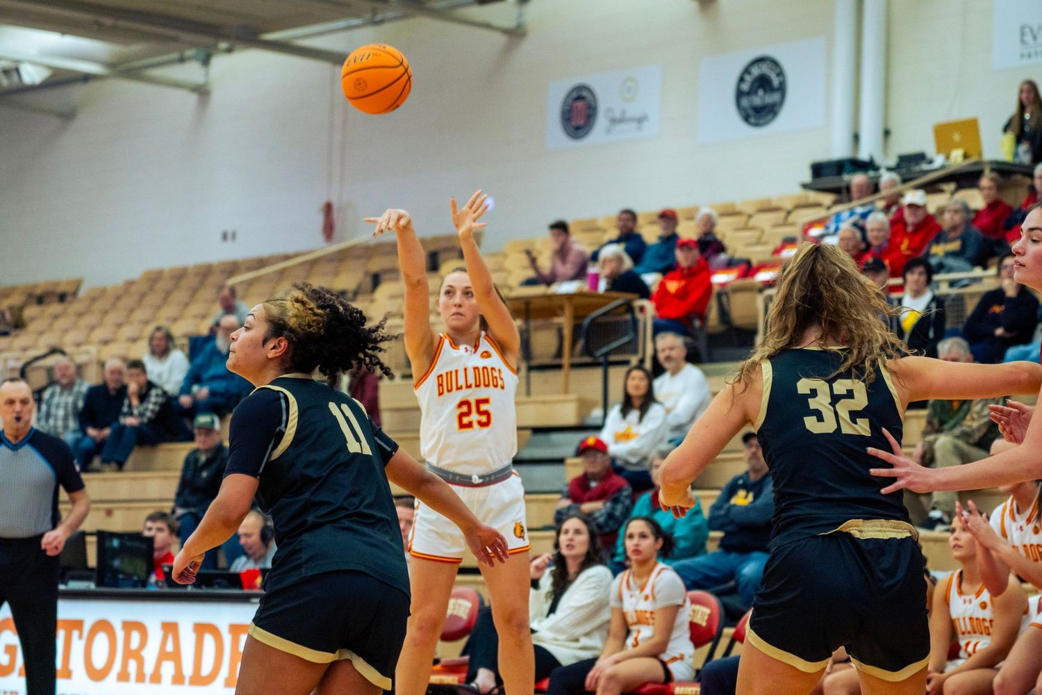 Basketball players compete for a rebound during an intense game in a packed gymnasium.