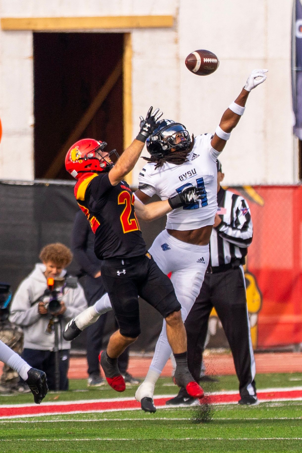 A football player dives horizontally to catch a pass during a game on a grass field.