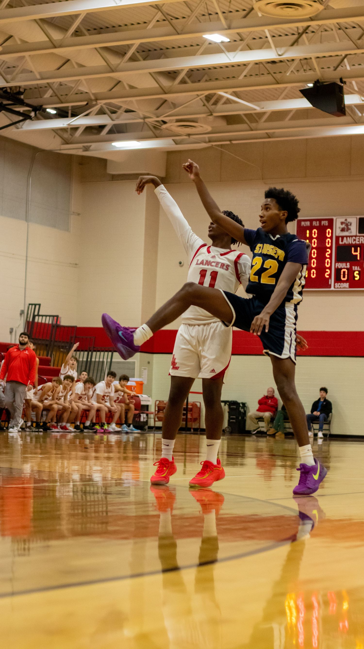 Basketball players showcase colorful footwear during an intense game in a school gymnasium.