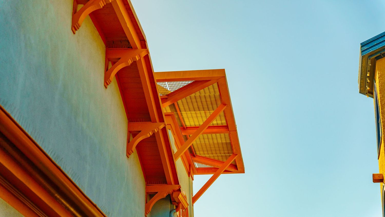 Low angle view of orange wooden balconies against blue sky.