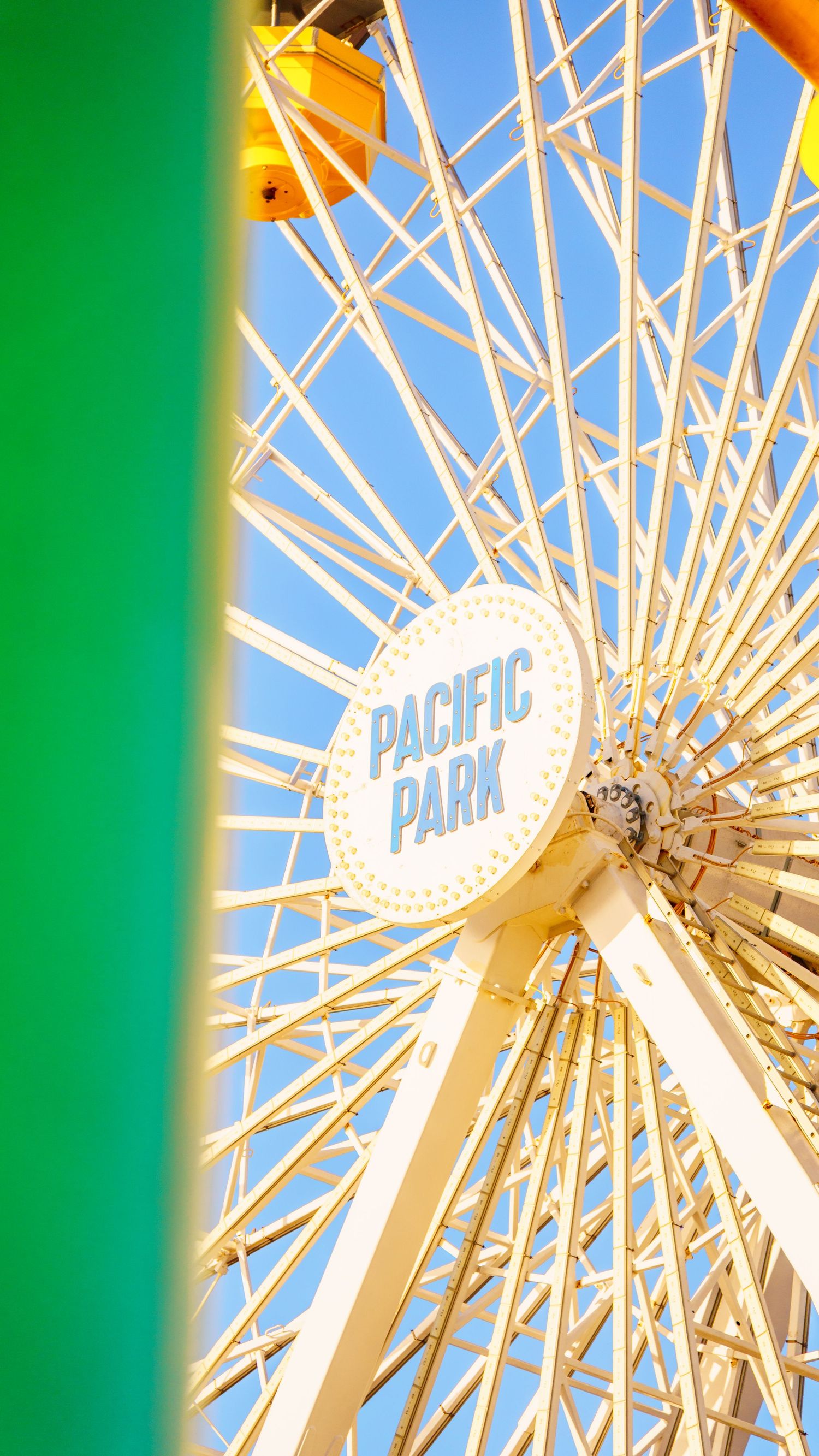 Close-up of Pacific Park's iconic Ferris wheel with bright white spokes against blue sky.