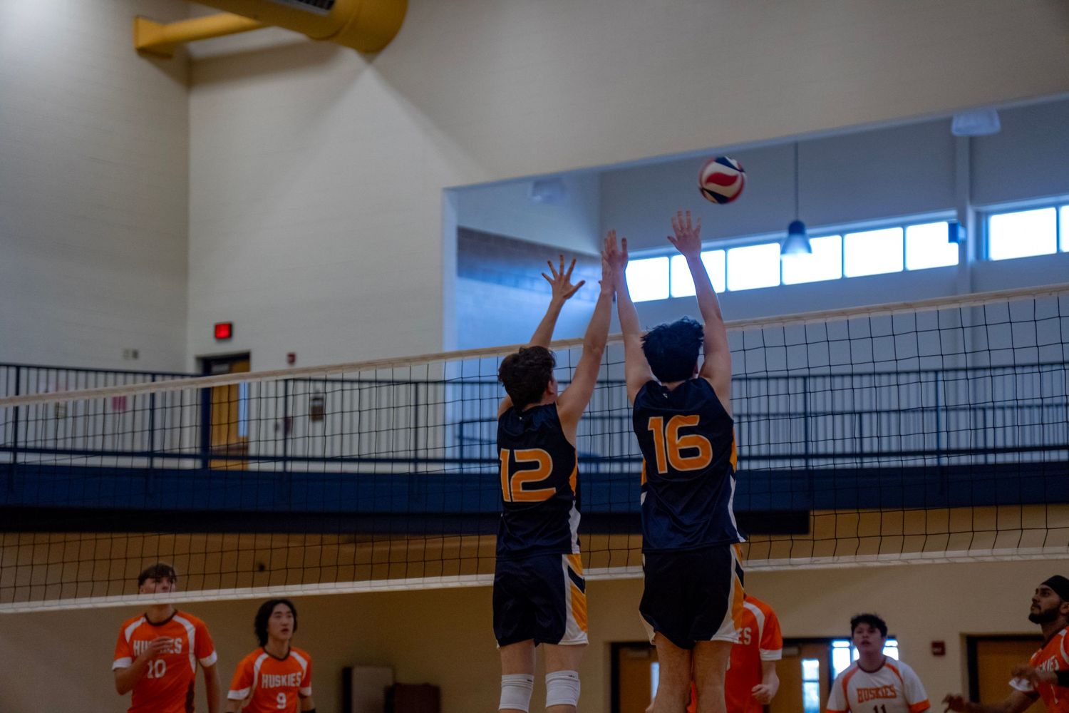Players from opposing teams battle at the net during a competitive volleyball match.