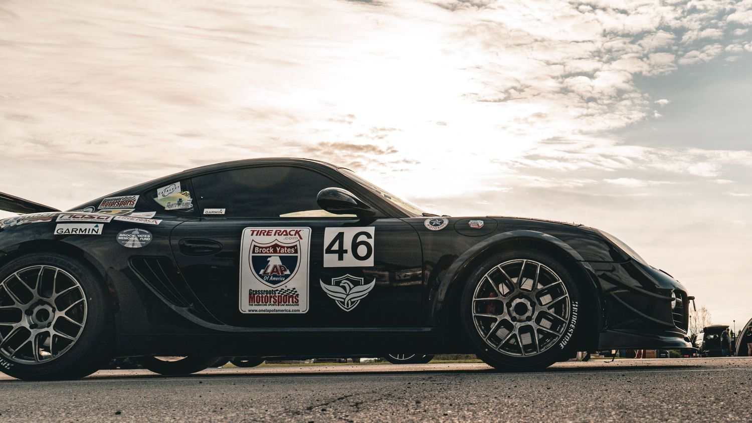 Panoramic view of black racing cars lined up on asphalt track.