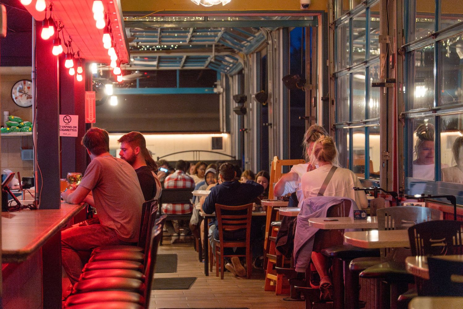 Red pendant lights illuminate a cozy restaurant interior with industrial-style decor and exposed ceiling beams.