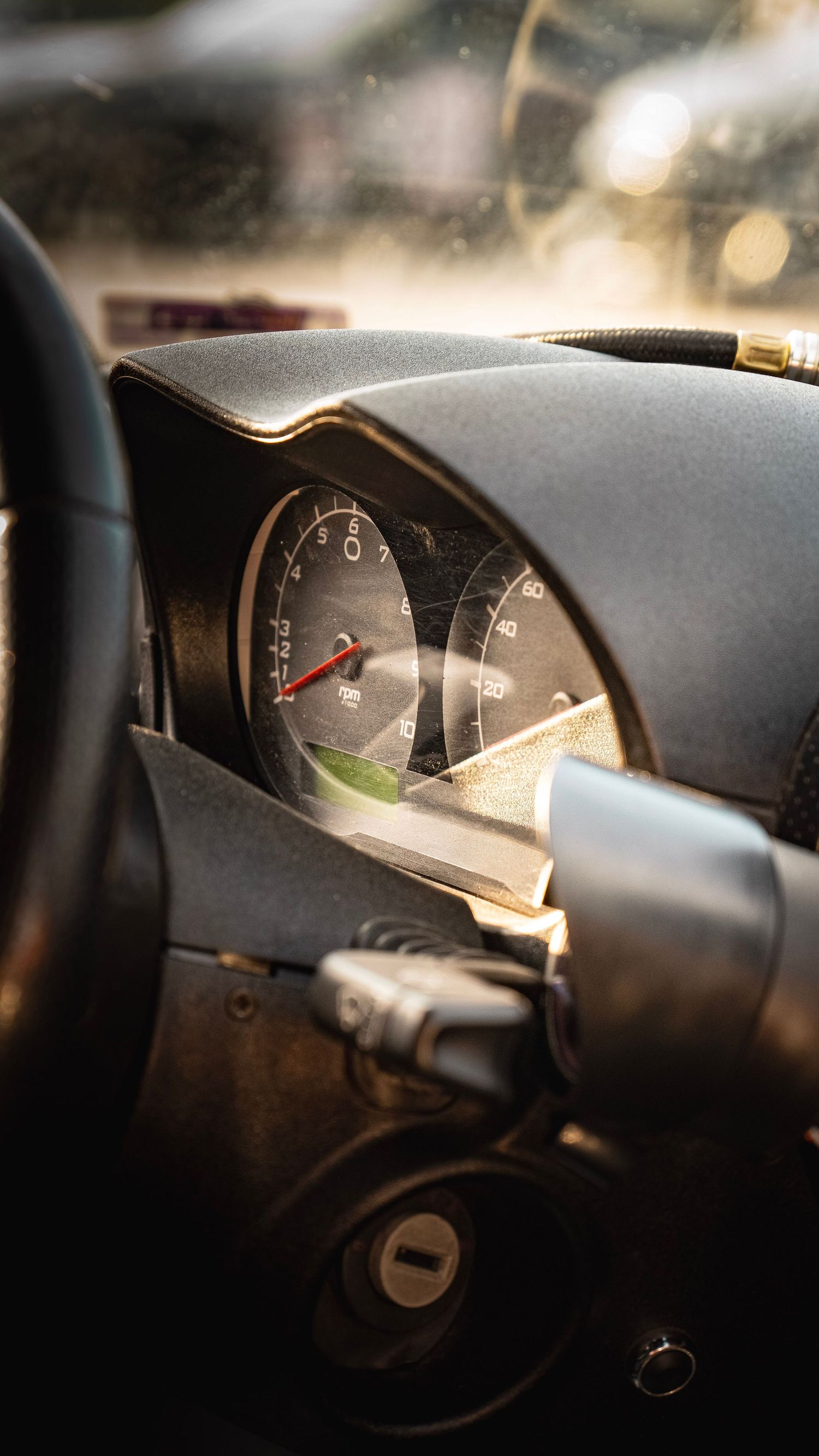 Interior dashboard gauges photographed through steering wheel in dramatic lighting.
