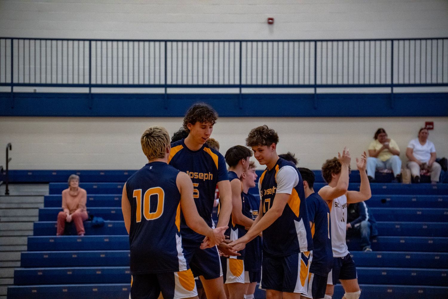 Wide view of volleyball court showing players and bleachers during a match.