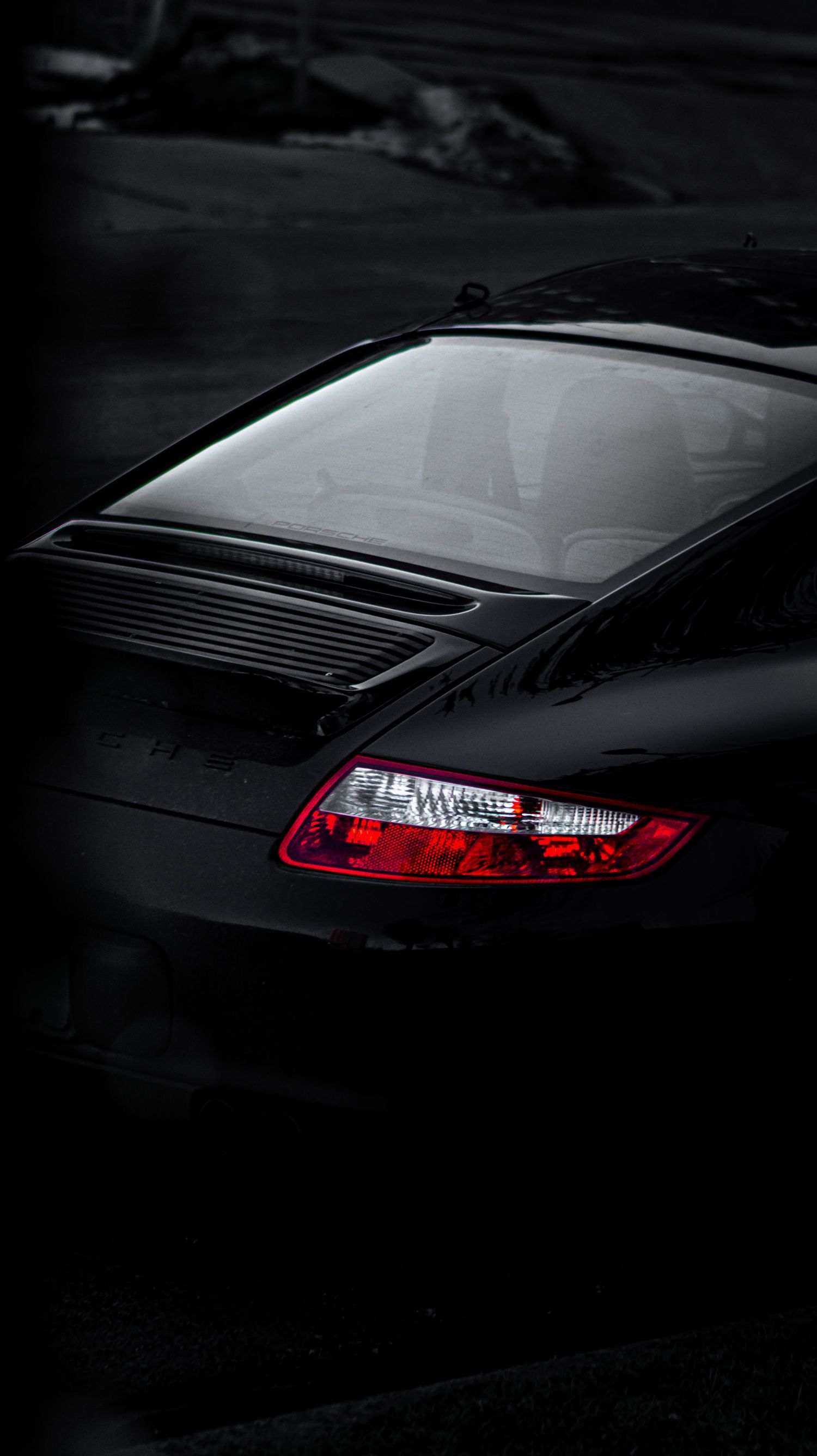 Rear detail shot of black Porsche 911 with distinctive LED taillights at dusk.