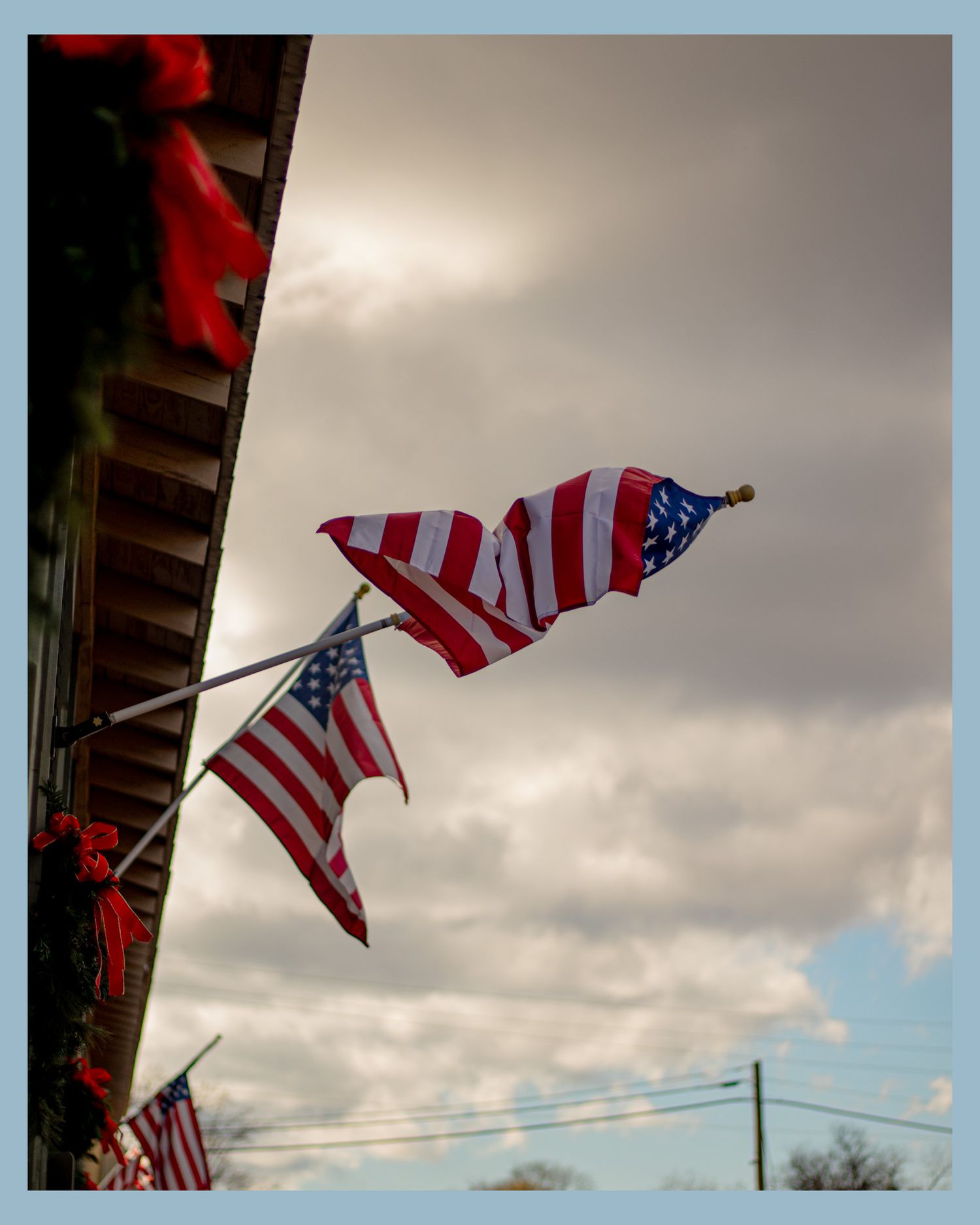 American flags waving in cloudy sky with patriotic decor.
