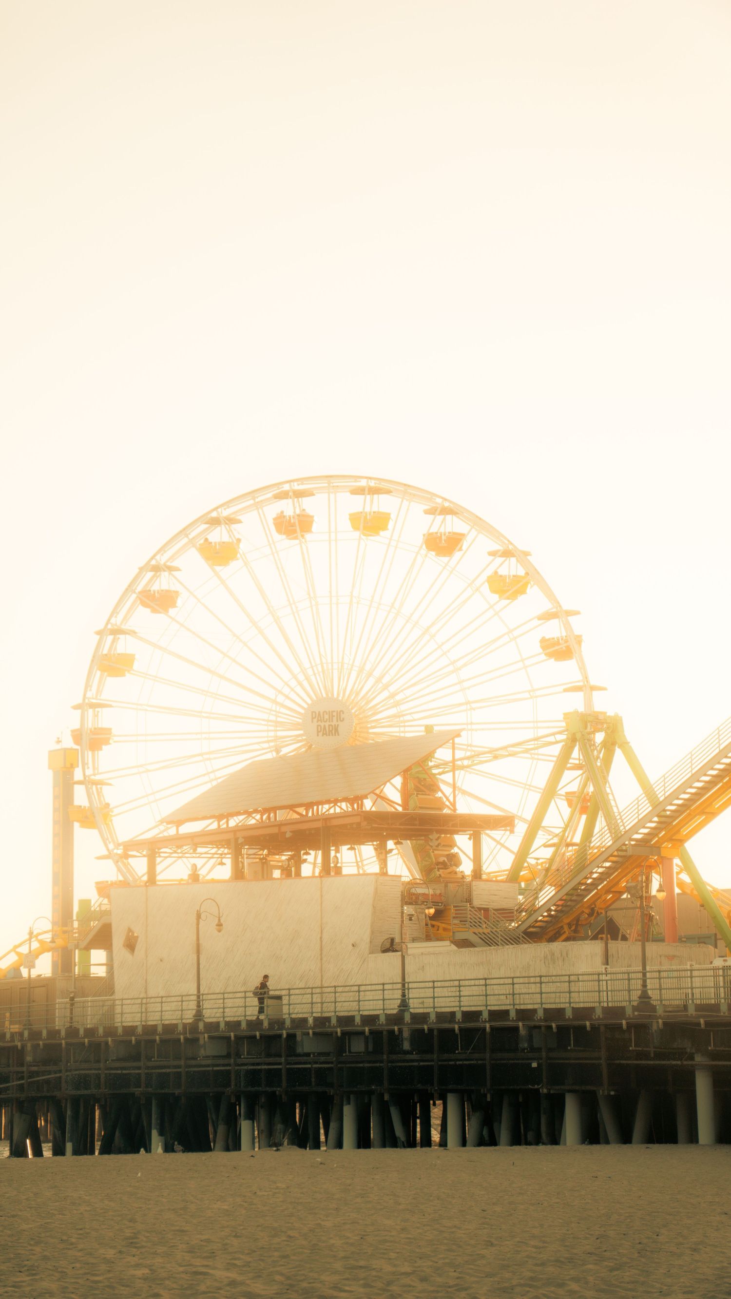 Misty sunset view of Santa Monica Pier with Ferris wheel creating dreamy silhouette.
