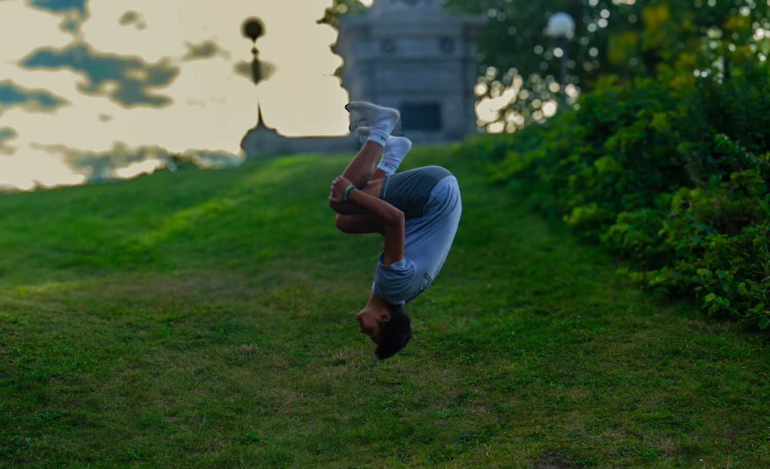Person executing an aerial backflip at sunset with a tower silhouetted in the background.