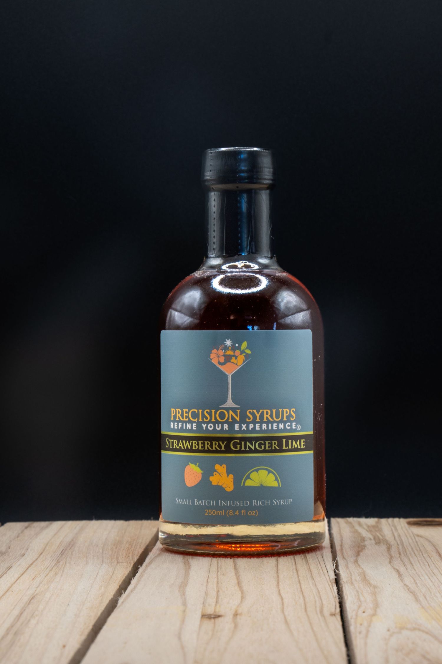 Bottle of artisanal cocktail syrup featuring ginger lime flavor on rustic wooden surface.