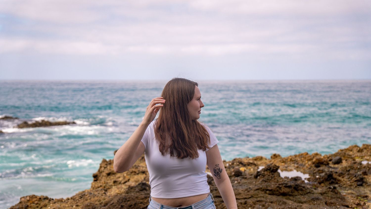 Candid seaside moment captured against dramatic rocky coastal landscape.