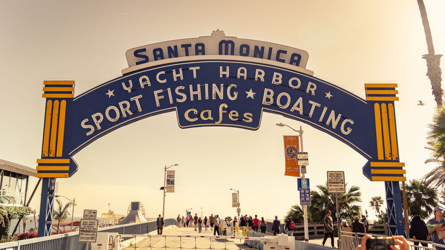 Iconic Santa Monica Yacht Harbor entrance arch with text for sport fishing and boating against blue sky.