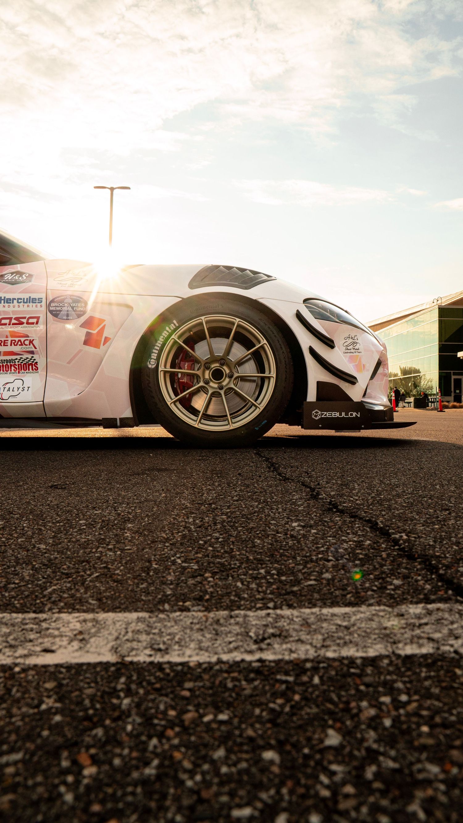 Ground level shot of white race car showing custom wheels and aerodynamic modifications.