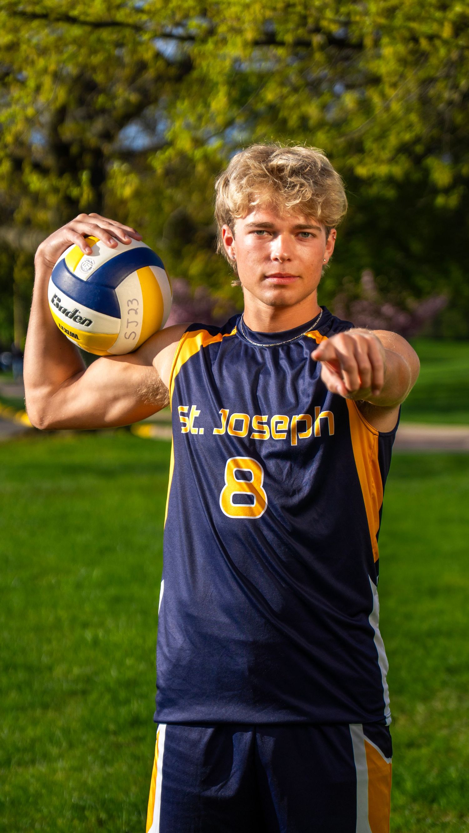 St. Joseph volleyball player number 8 poses with ball in athletic stance outdoors.