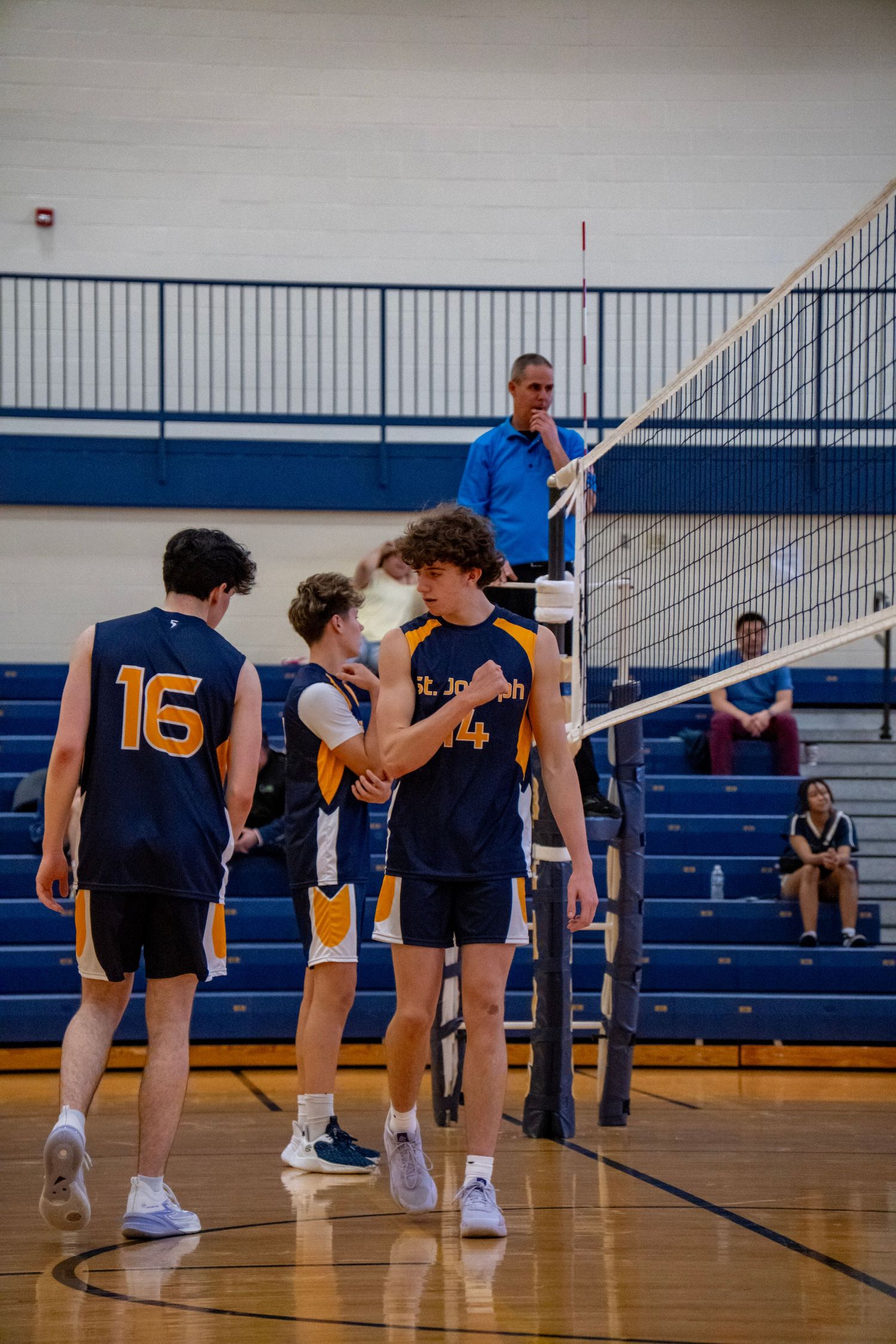 Indoor volleyball team warming up before a game, stretching near the net.