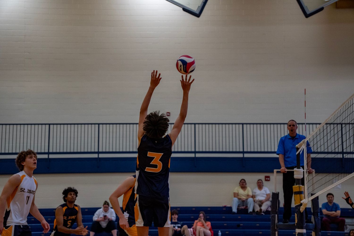 A volleyball player jumps to set the ball during an indoor game.