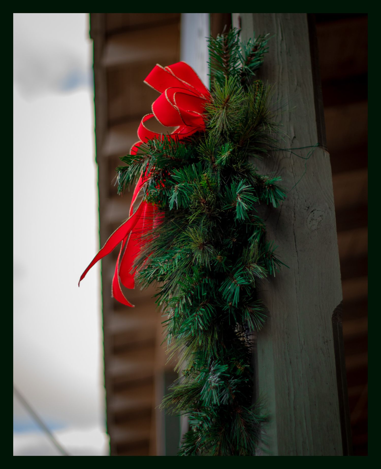 Christmas greenery with red bow decorating outdoor column.