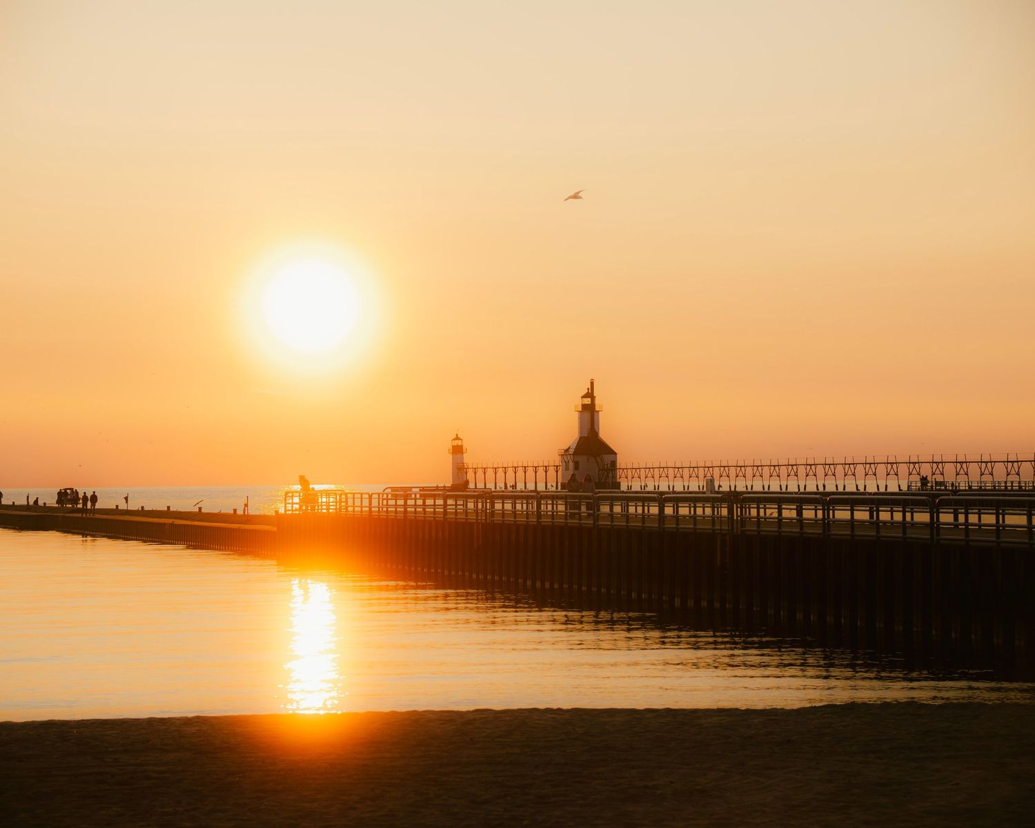 Historic lighthouse and catwalk create perfect silhouette against warm summer sunset.