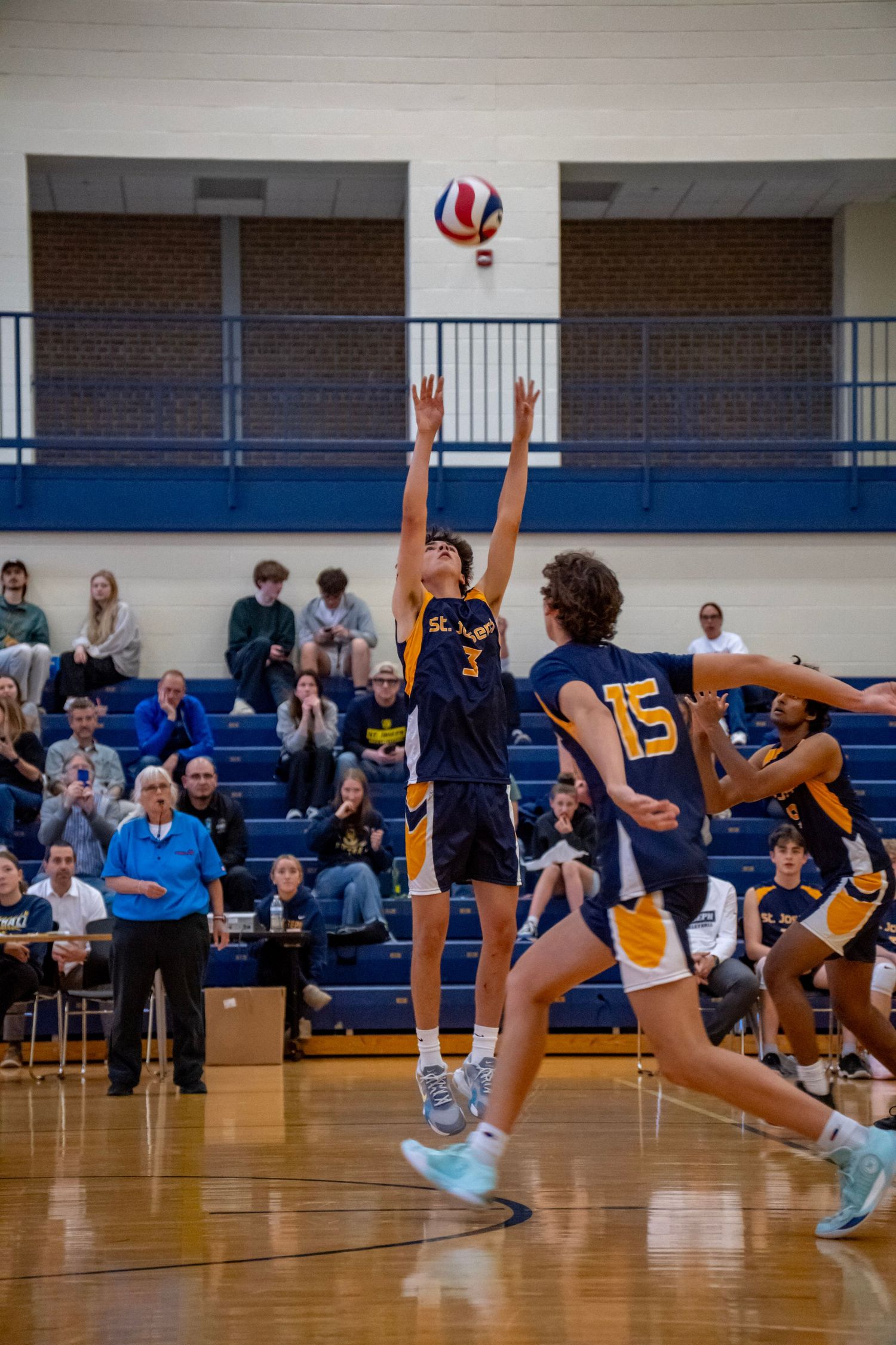 A volleyball player jumps to block the ball during an intense game moment.