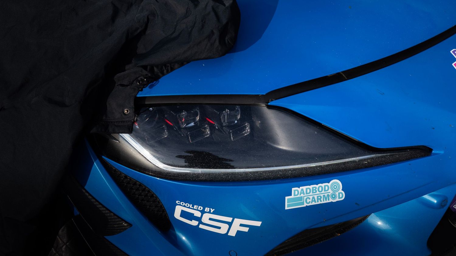 Close-up detail shots of blue sports car exterior parts and bodywork in dramatic lighting.