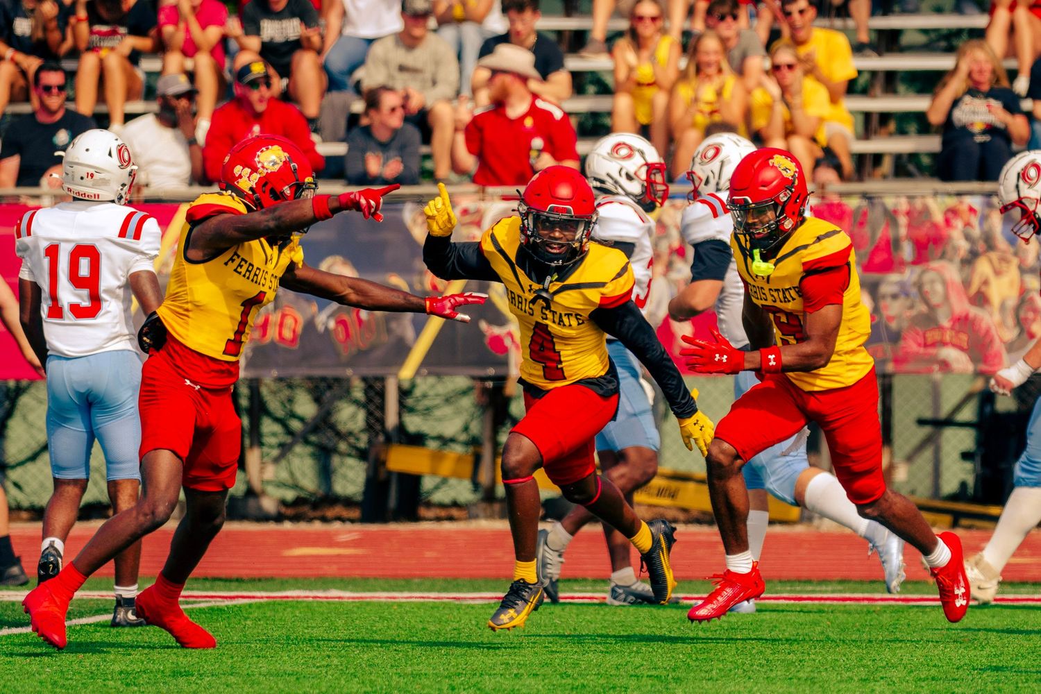 Football players in red and yellow uniforms clash during an intense play on the field during a game.