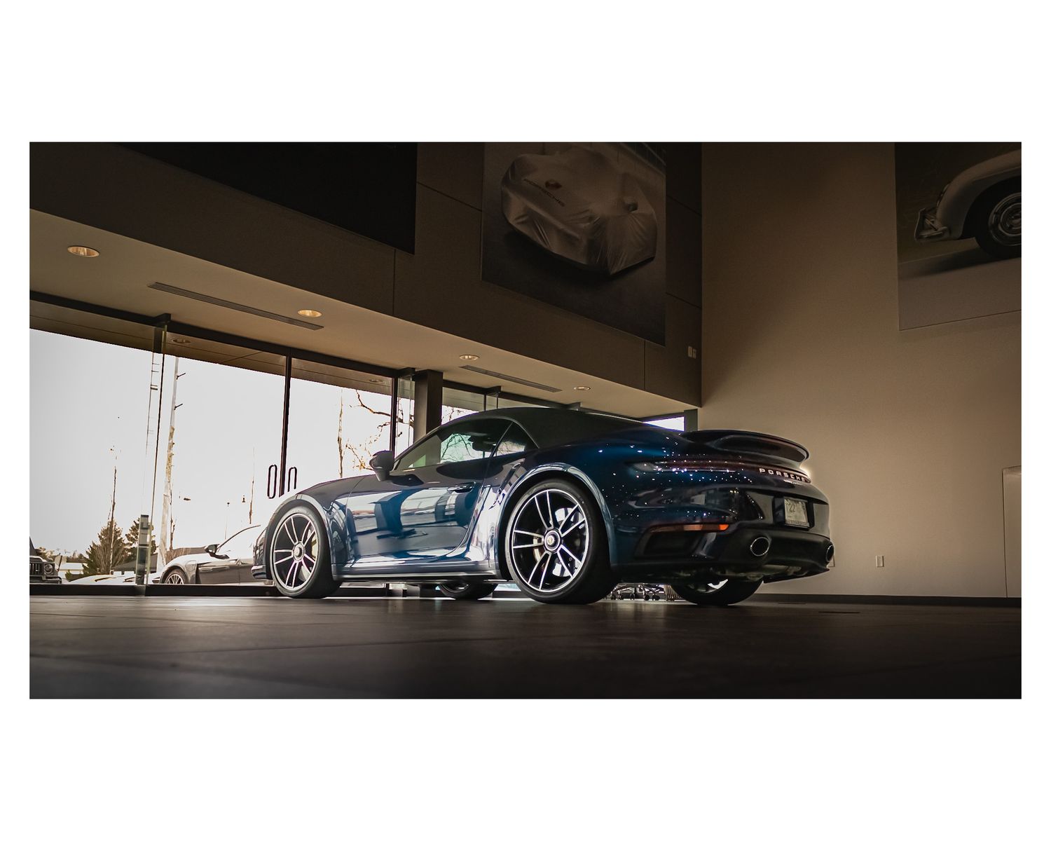 Side view of a blue Porsche 911 sports car in a showroom setting.