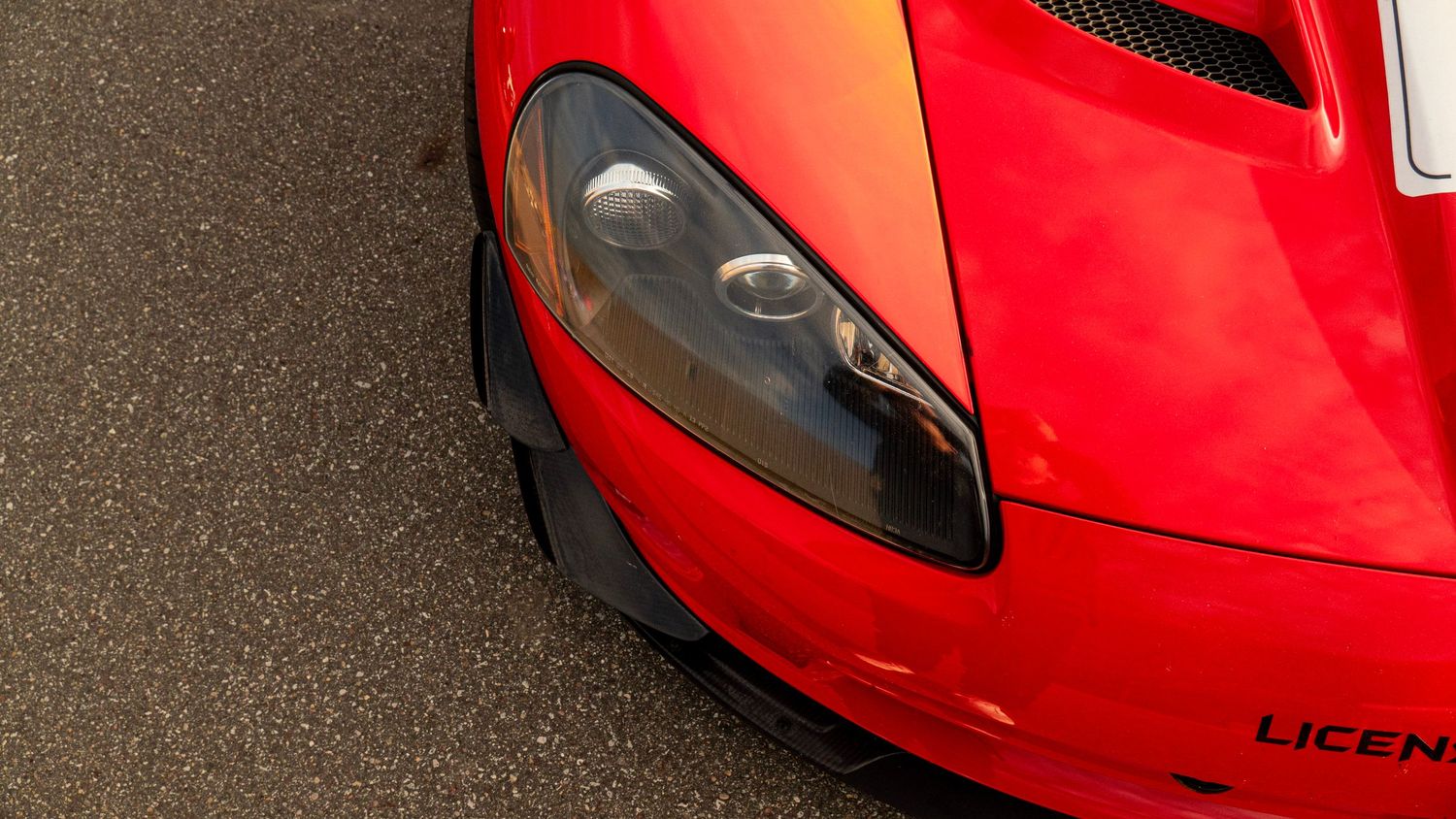 Detail shot of red Dodge Viper headlight and front bumper against dark background.