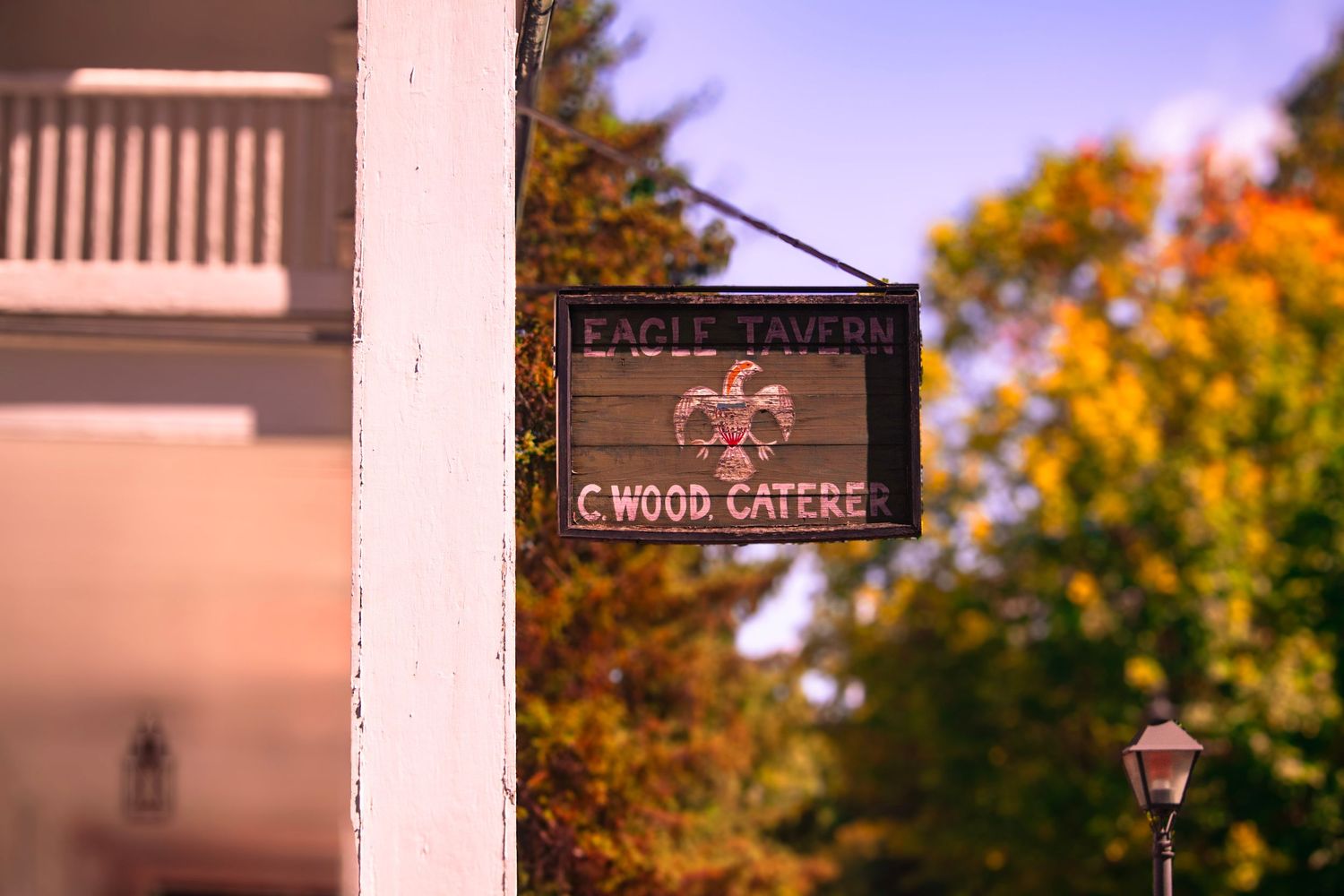Vintage wood gateway sign hanging from post with autumn colors in background.