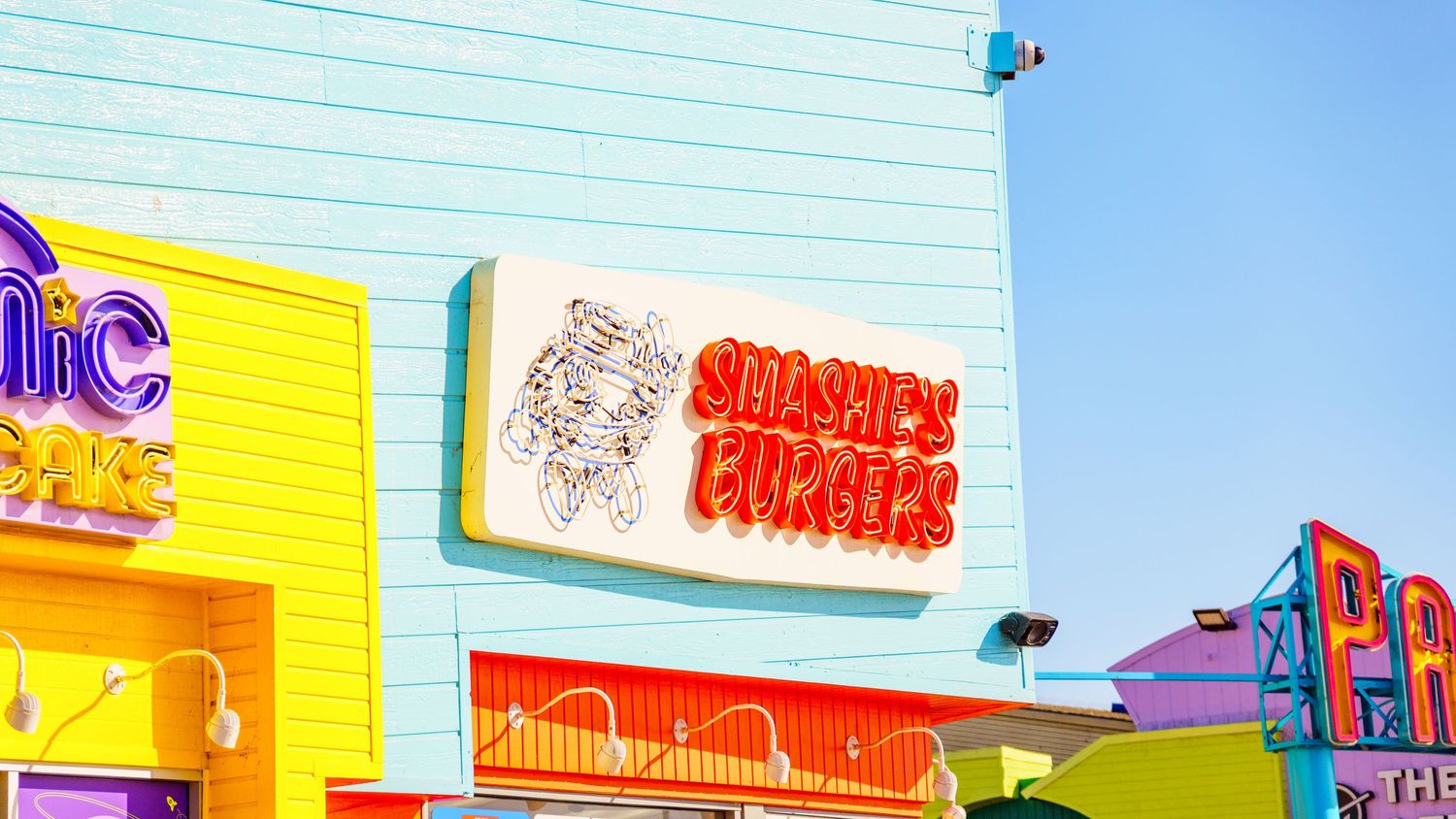 Retro-styled storefronts with bright pastel colors at an amusement park.
