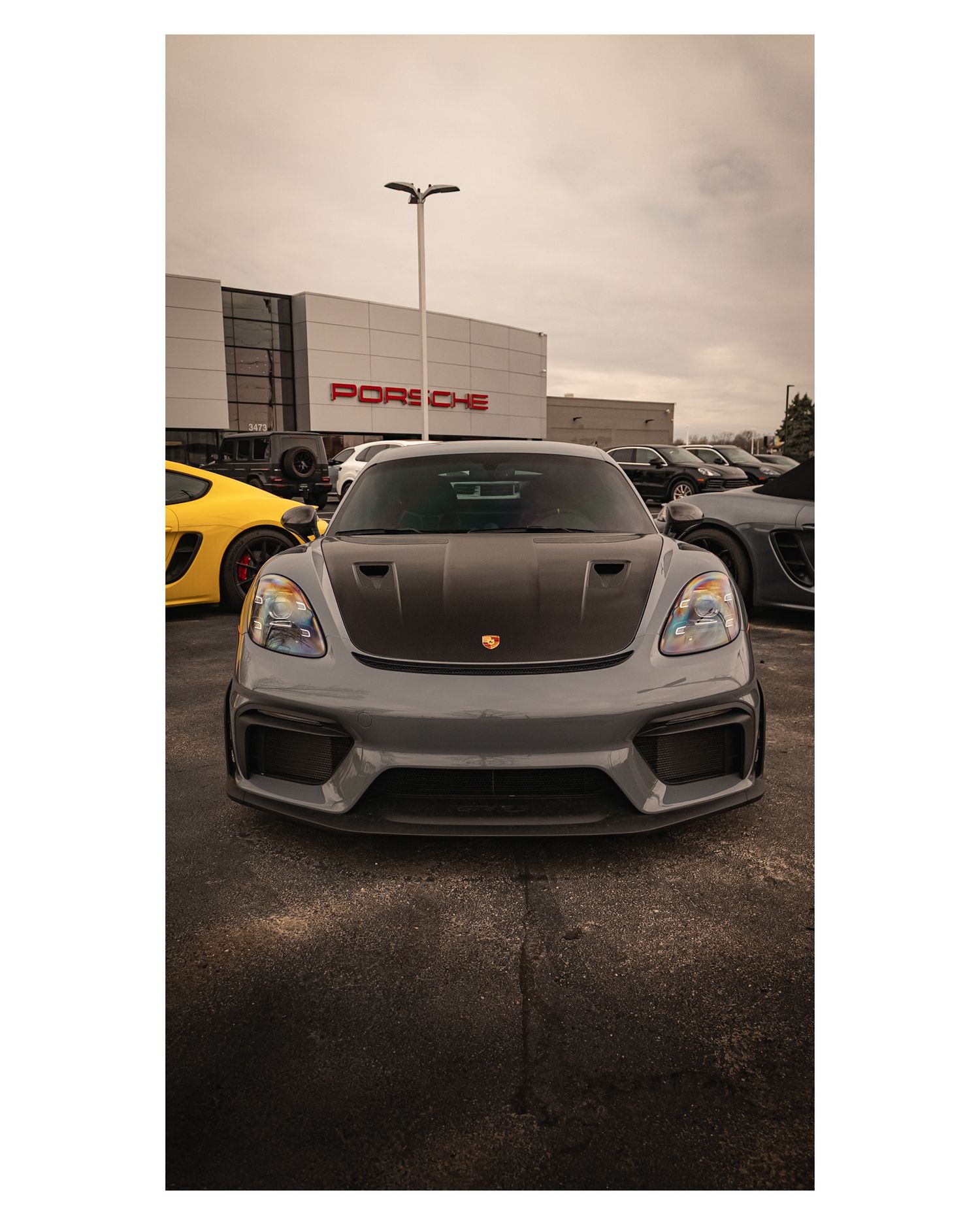 Front view of a gray Porsche GT4RS parked outside a Porsche dealership.