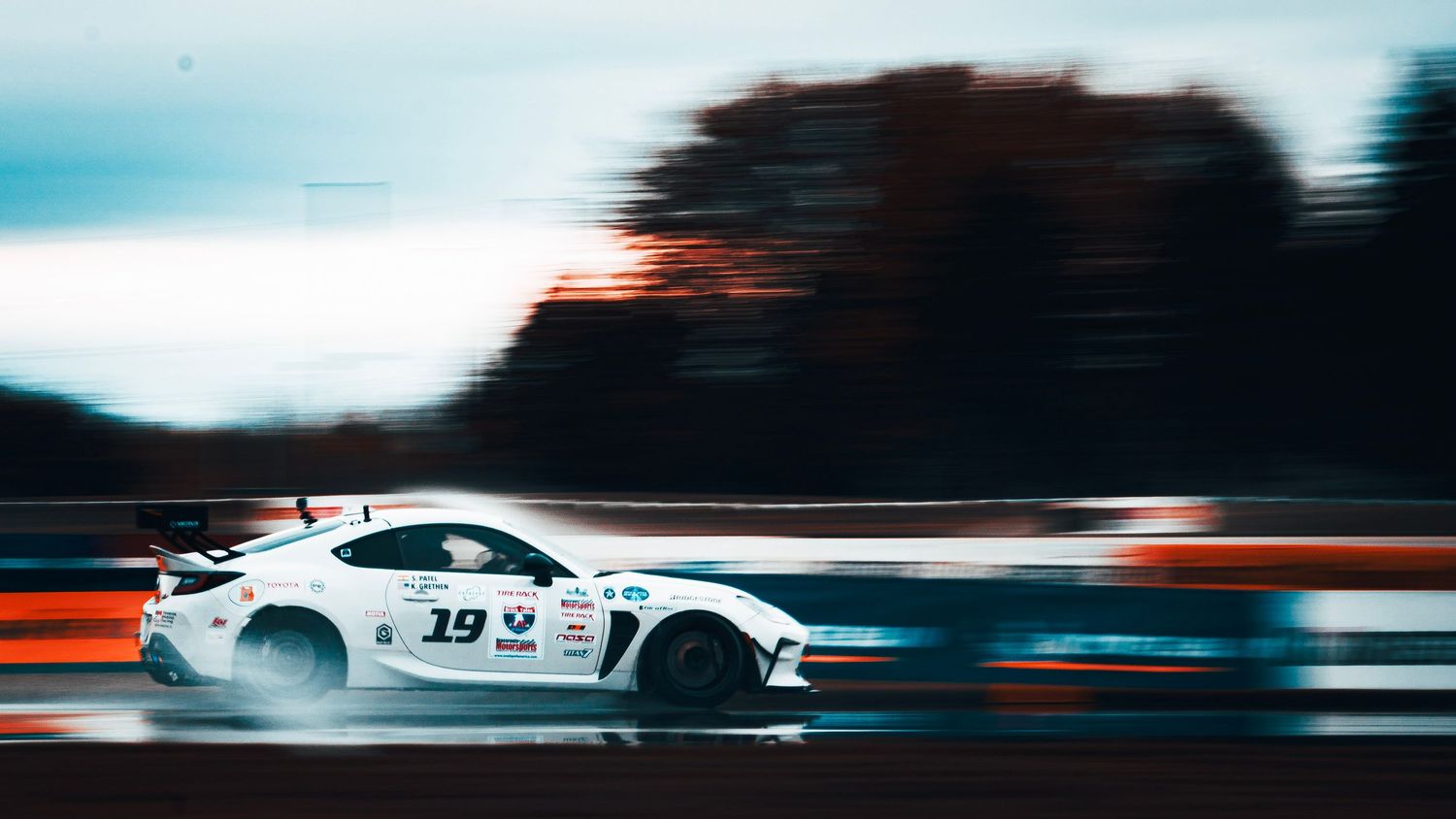 High-speed racing cars creating dramatic motion blur on a motorsport track.