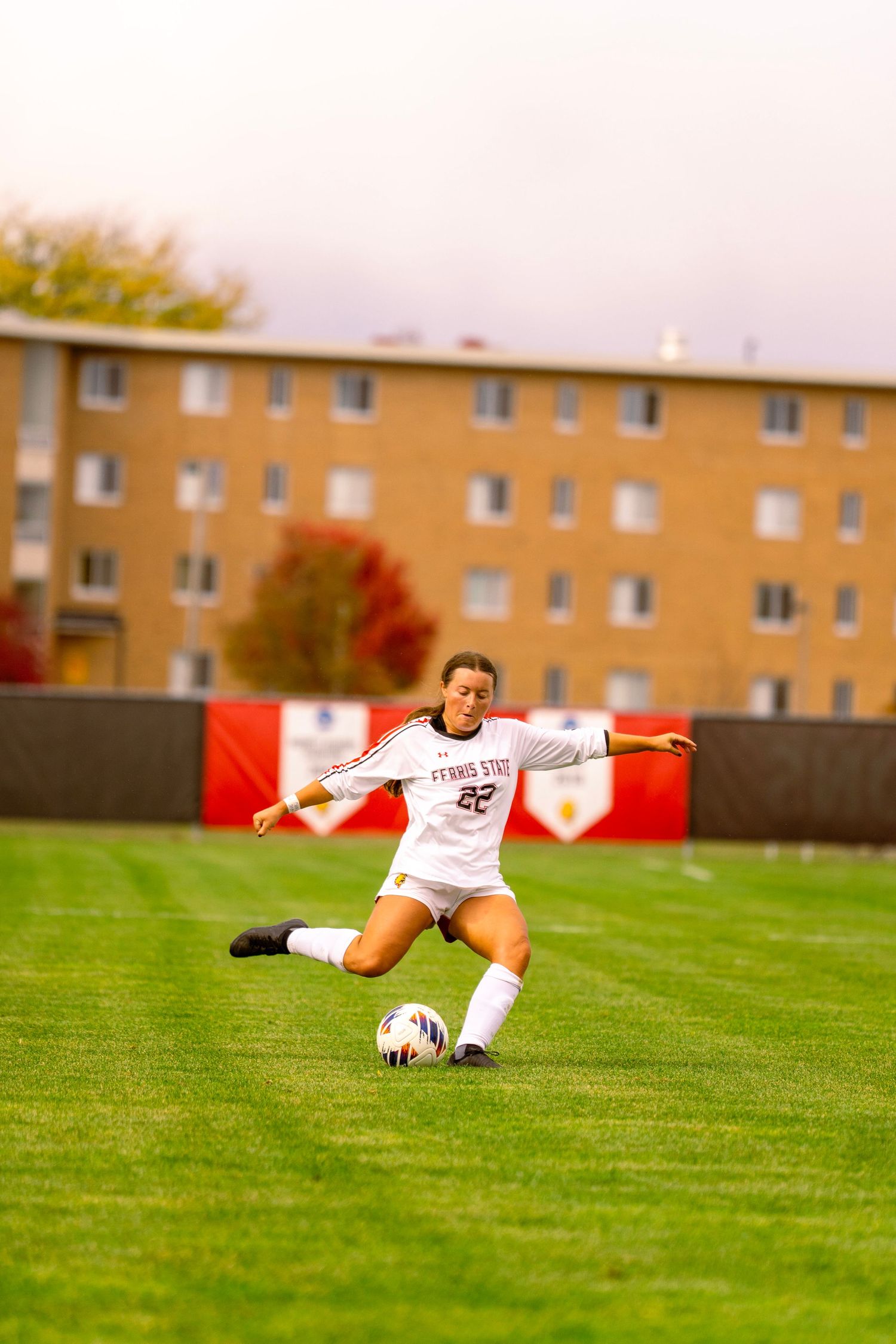 A soccer player slides across a green grass field while making a save during a match.