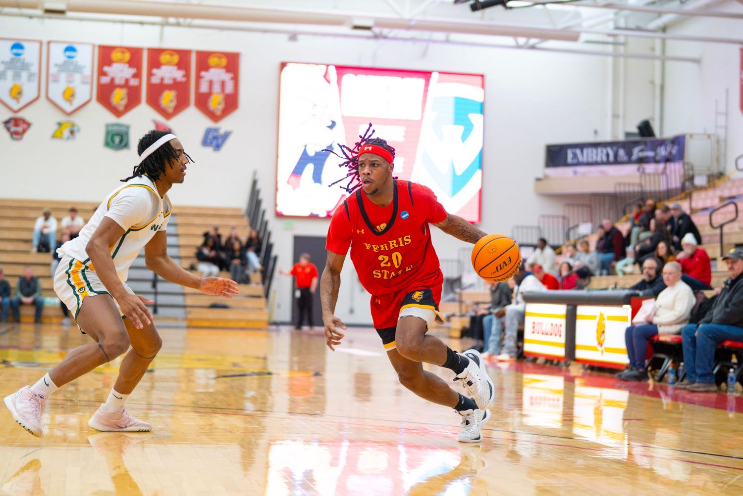 Basketball player in red uniform dribbles past defender during competitive indoor game.