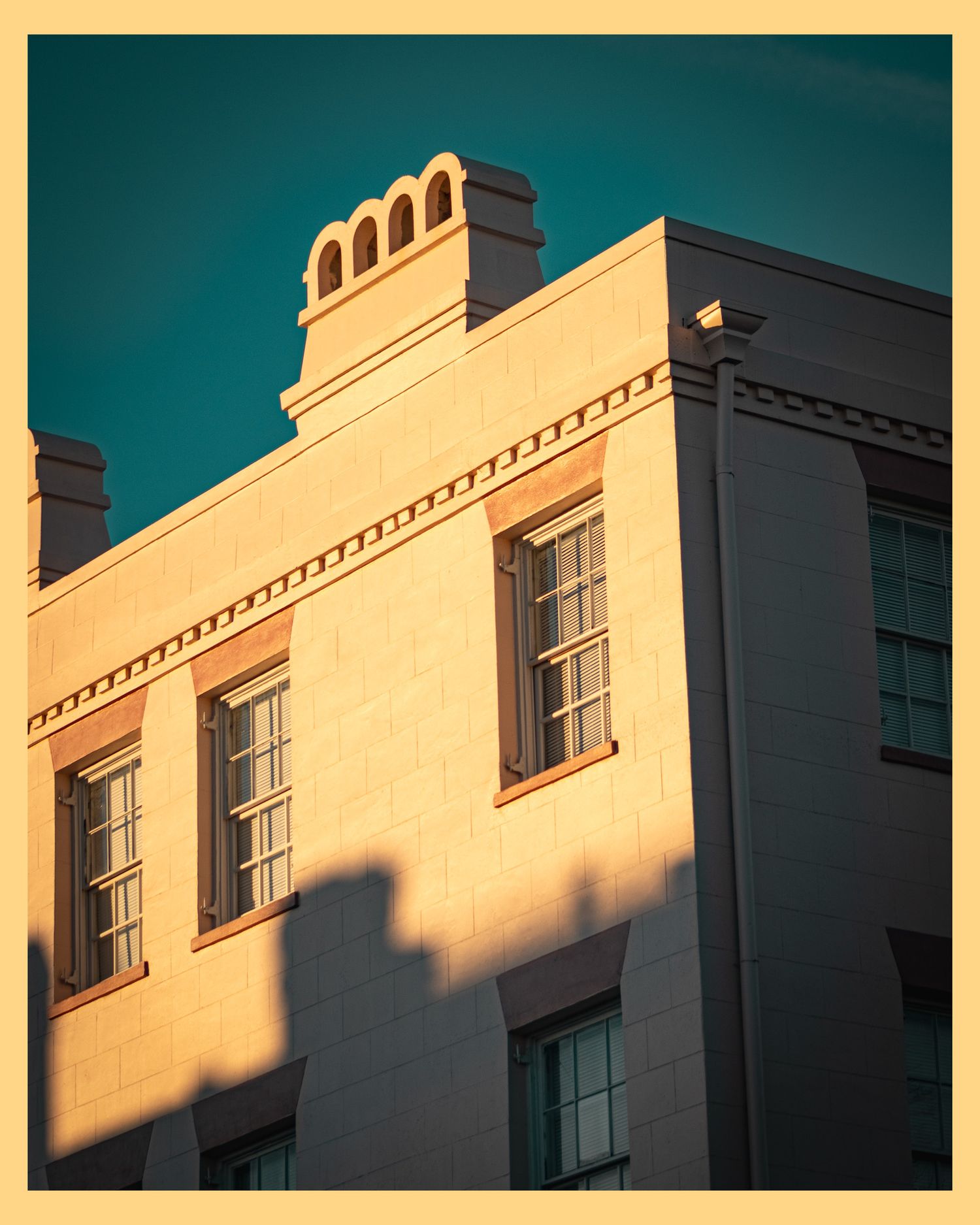 Classical white building facade with arched windows and decorative roofline in afternoon light.
