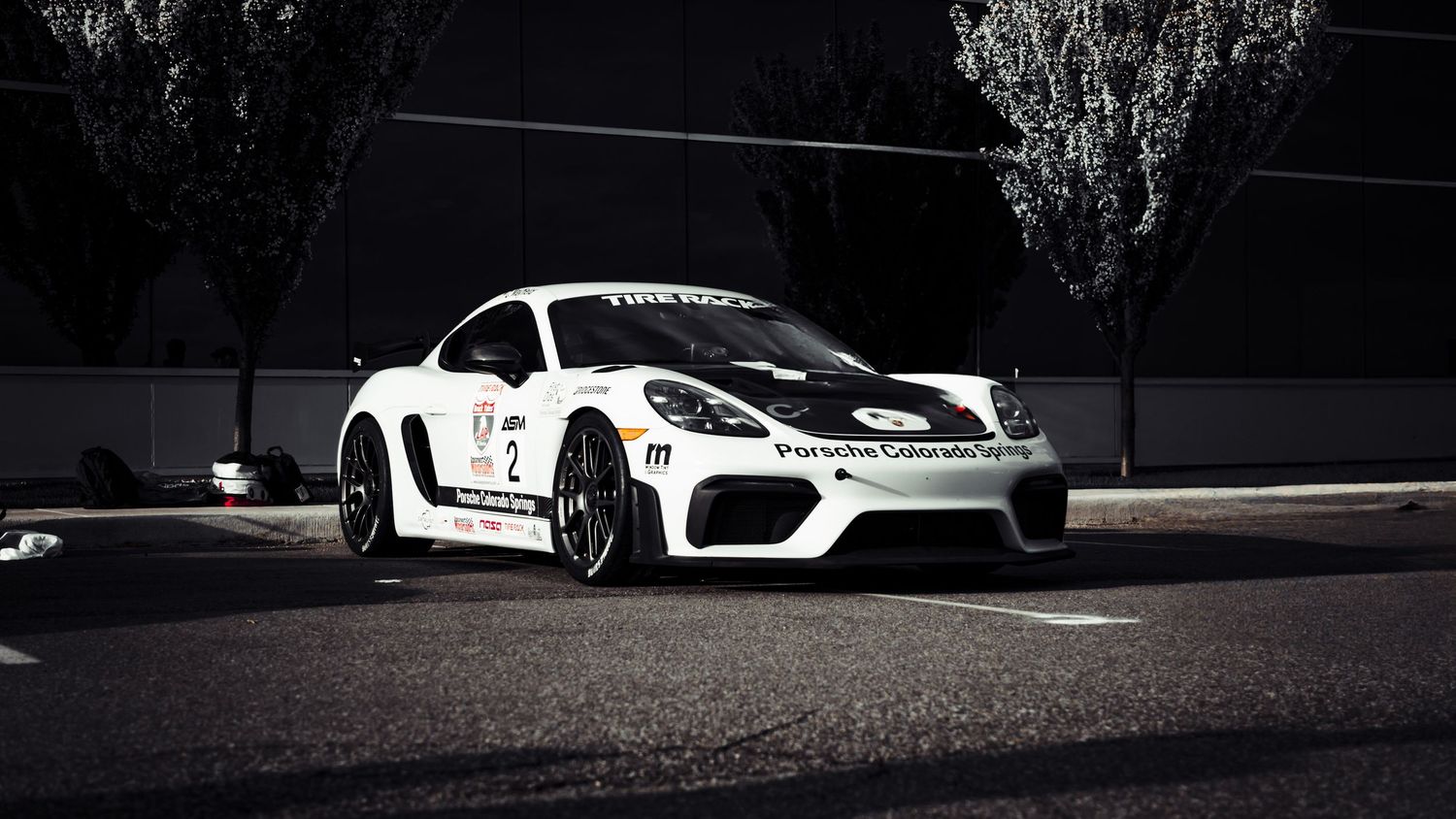 Silhouetted race cars lined up against dark background with dramatic lighting.