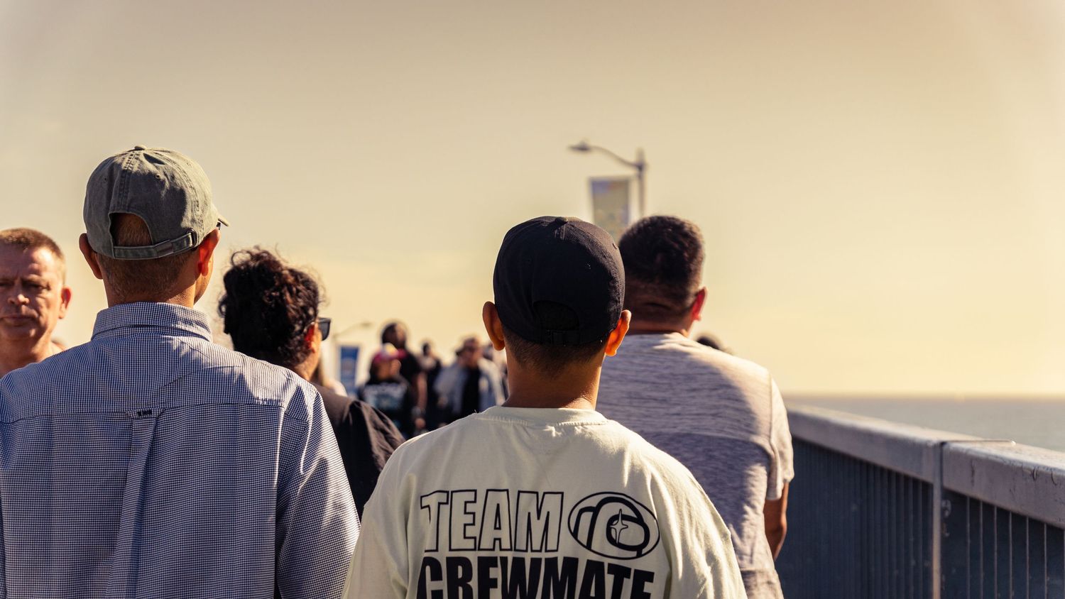 Crowd of people gathered on pier during sunset.