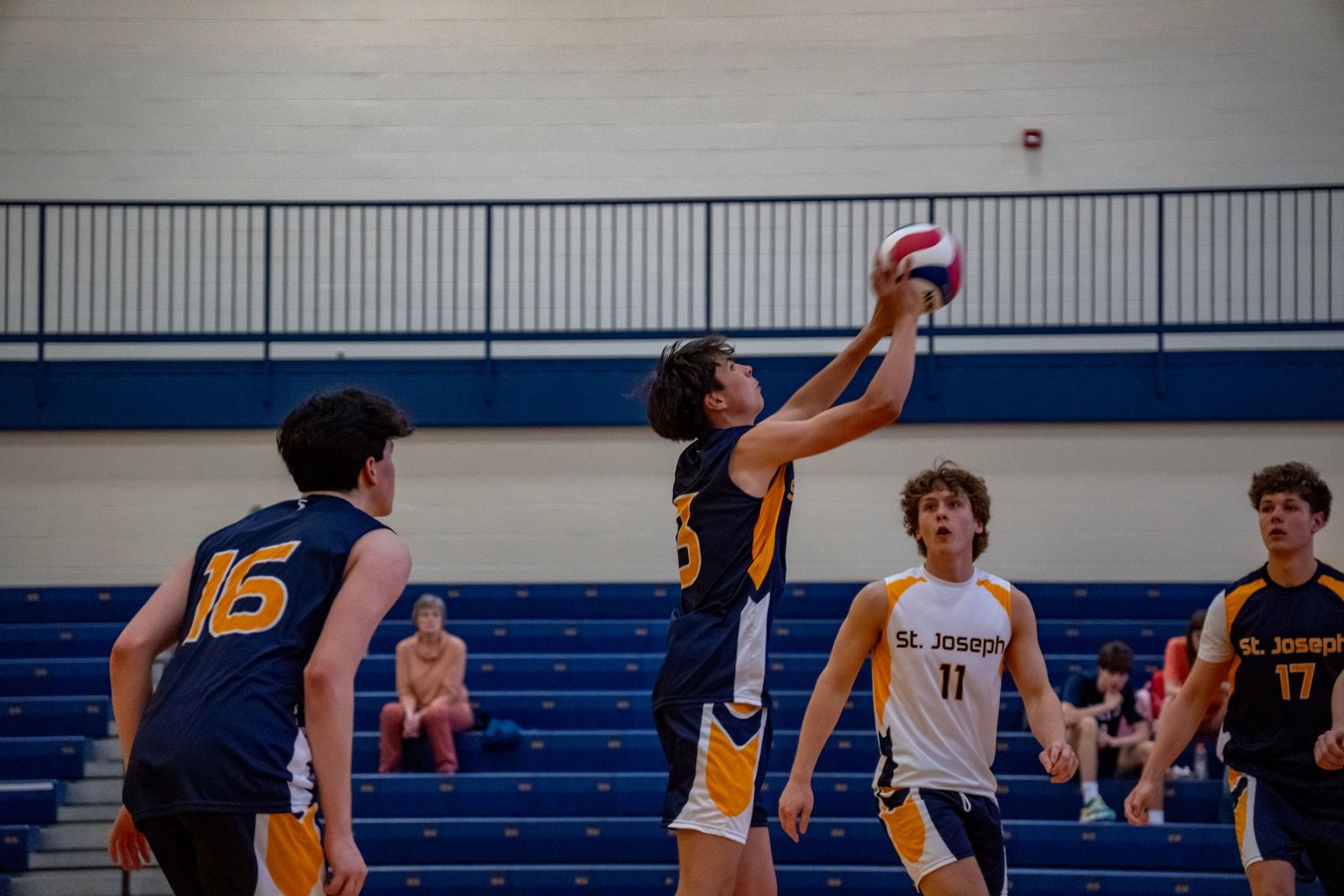 Players jumping high to block a volleyball shot during an intense indoor match.