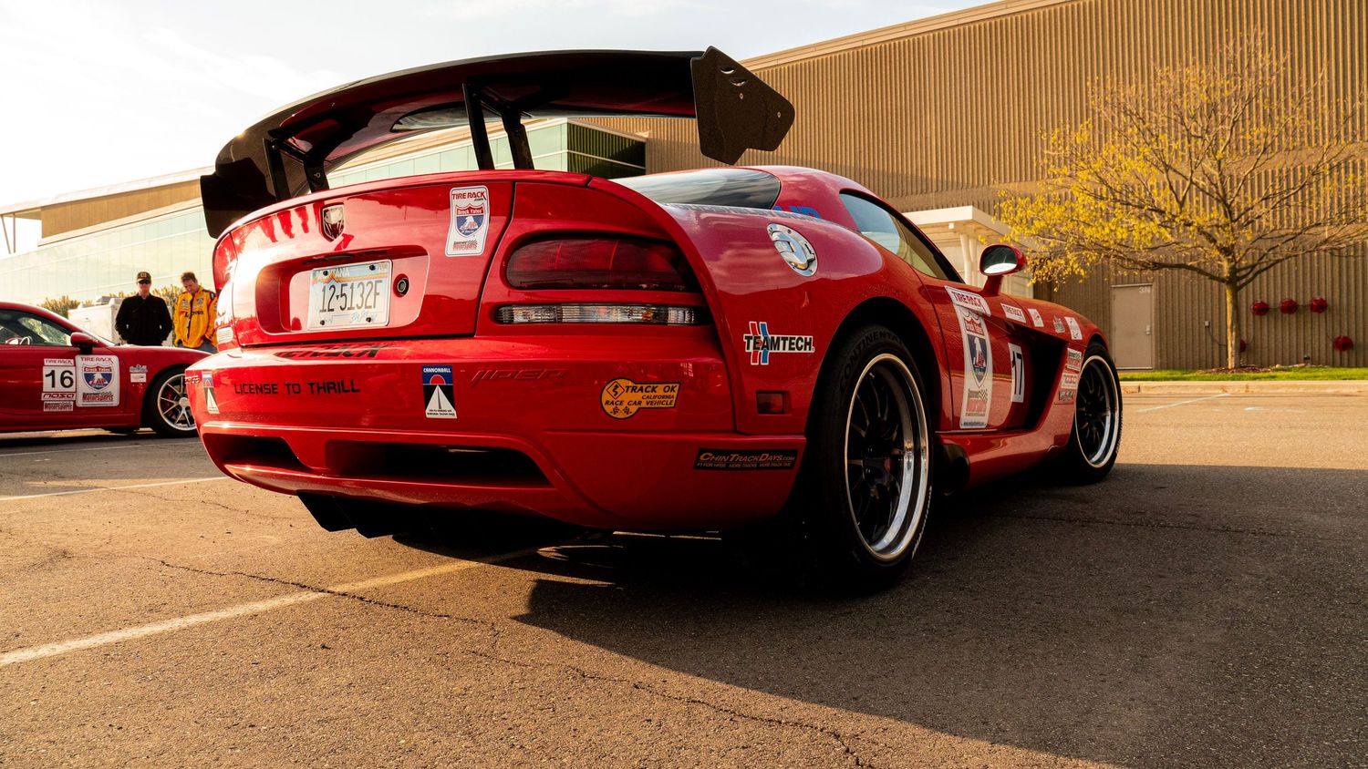 Modified red Dodge Viper with racing decals and wide body kit viewed from rear quarter angle.
