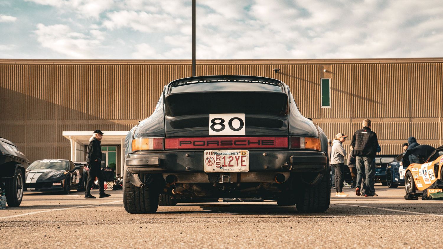 Rear view of a modified black Porsche 911 with racing number 80.