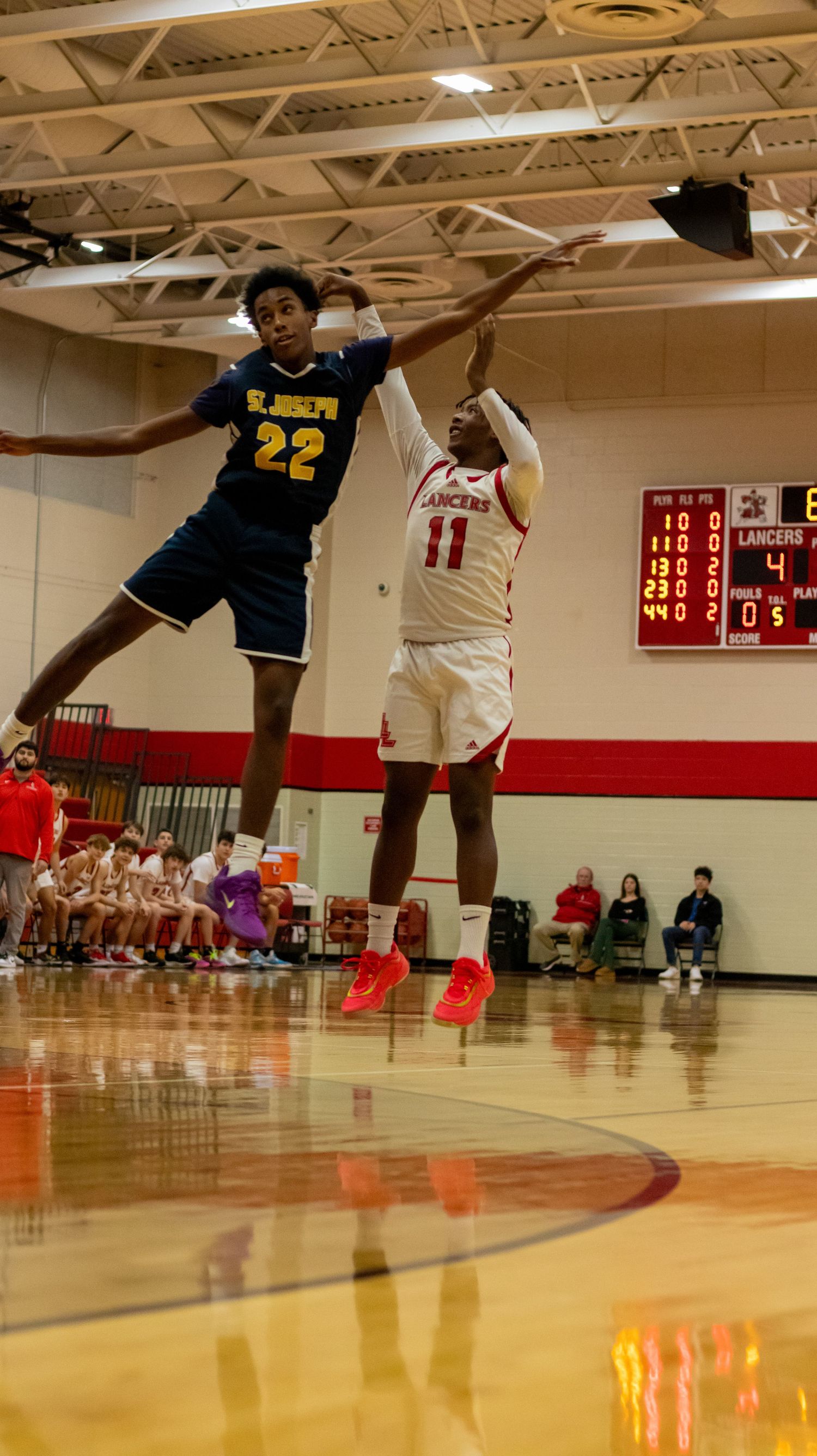Two basketball players jump high for the ball during intense game action.