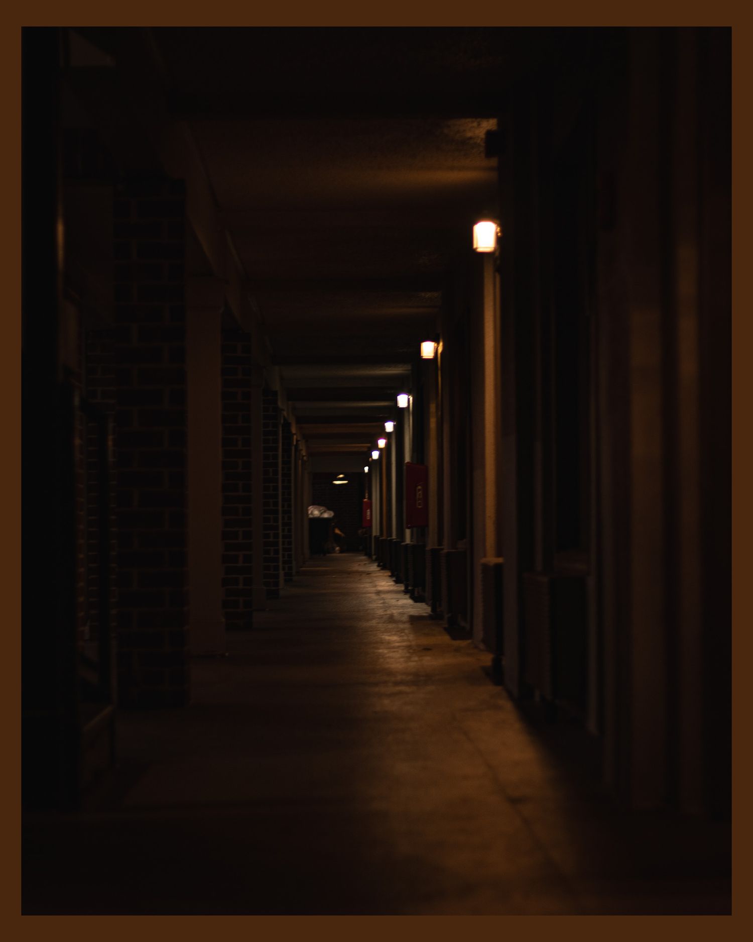 Dark corridor with glowing lights creating dramatic perspective down brick hallway.