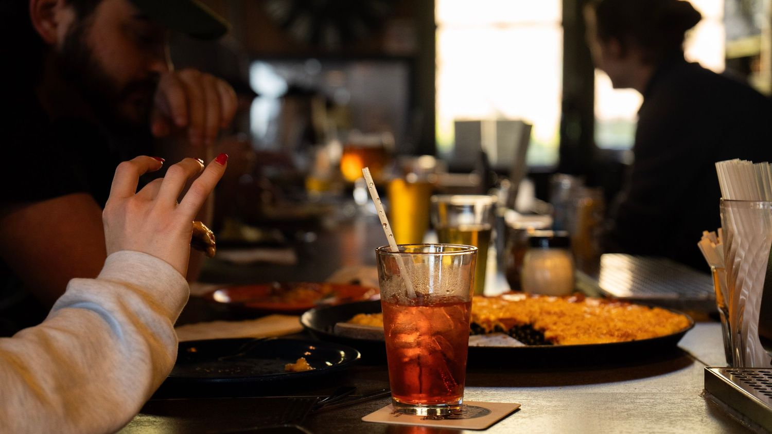 People dining at a dimly lit bar with cocktails and snacks in an intimate restaurant setting.