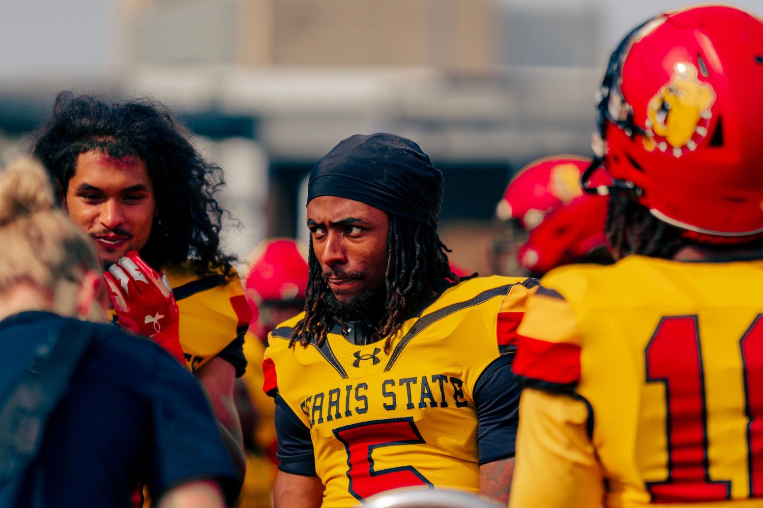 Football players in red and yellow uniforms huddle together during a game on the field.