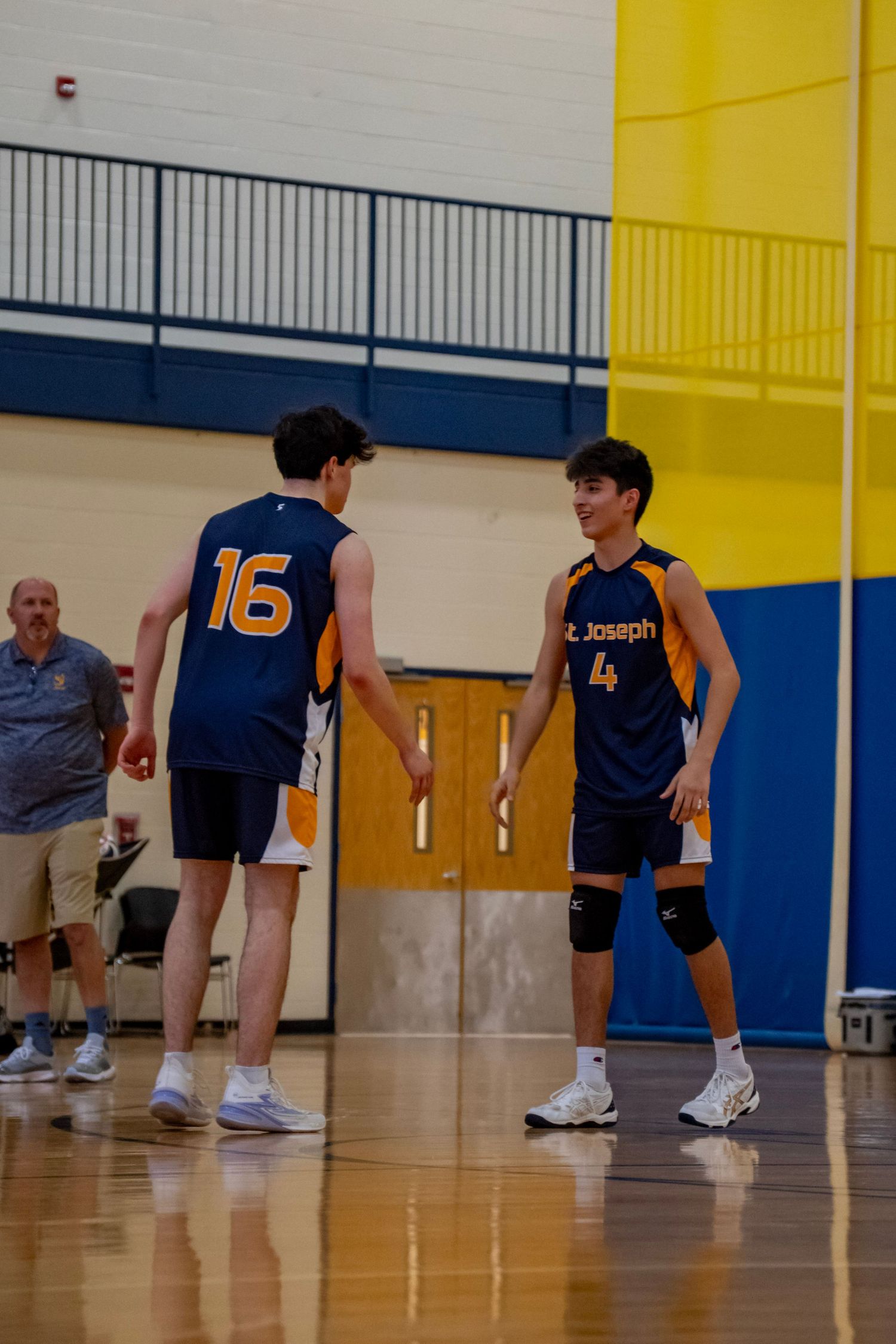 Two players in navy jerseys discuss strategy during a volleyball game break.