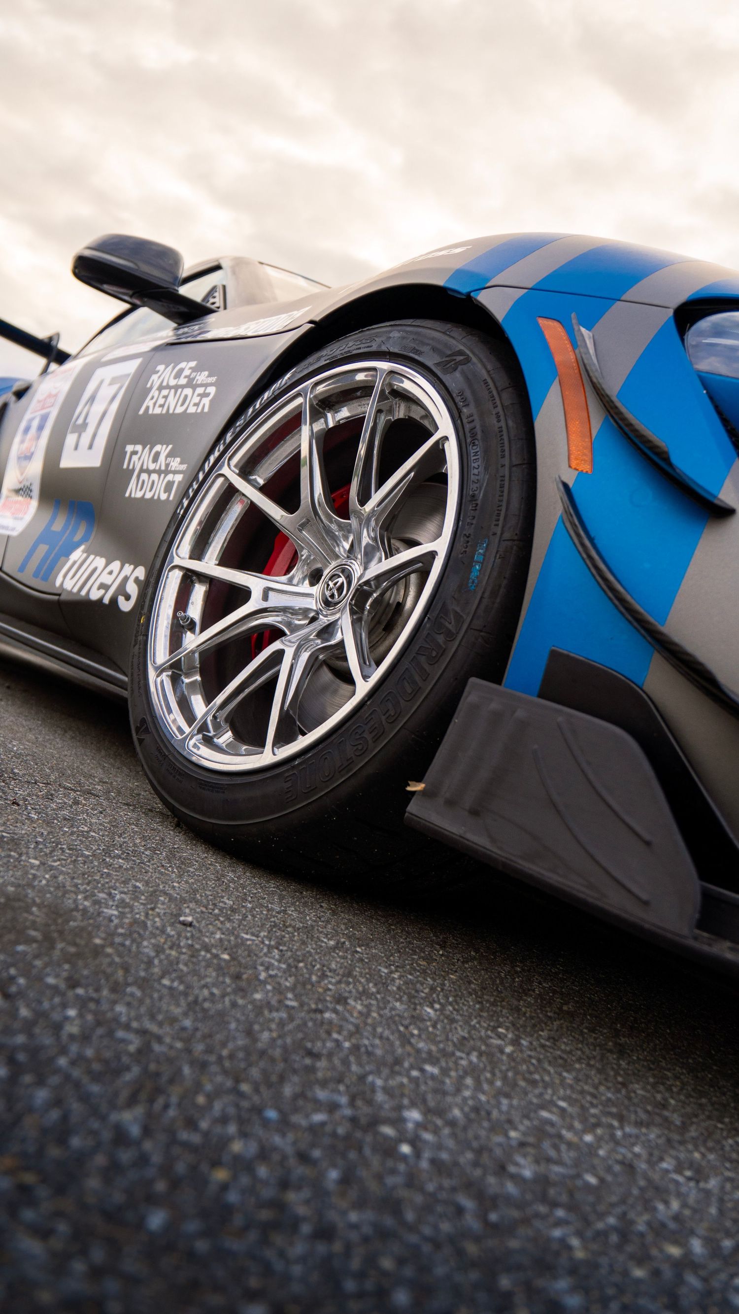 Close-up of a blue and black race car wheel with custom alloy rim and performance brakes.