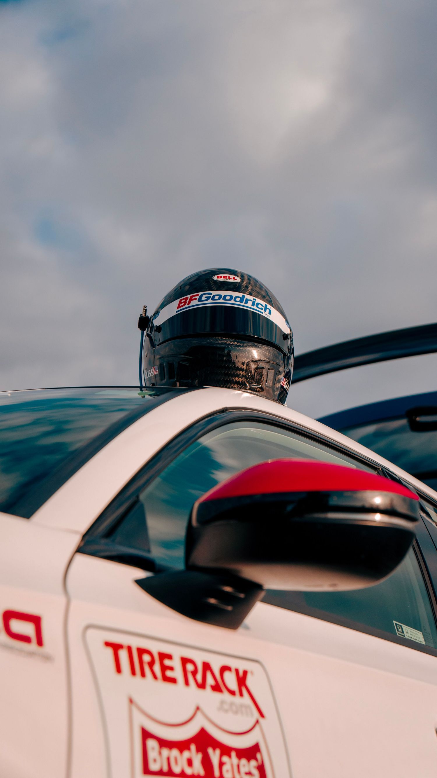 Racing helmet with BFGoodrich logo mounted on white car with Tire Rack branding.