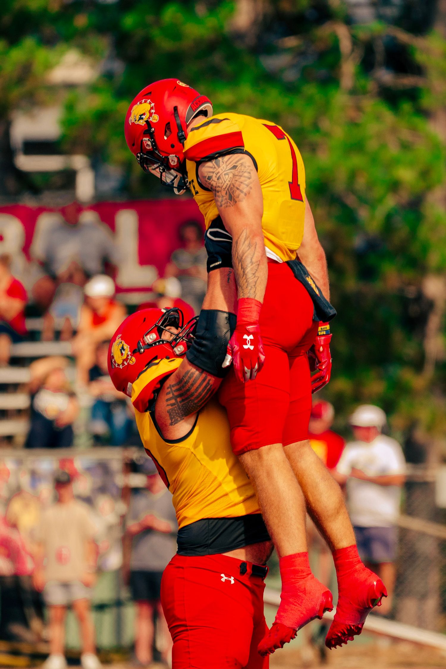 Two lifeguards in red and yellow uniforms demonstrate rescue techniques during training at an outdoor pool.