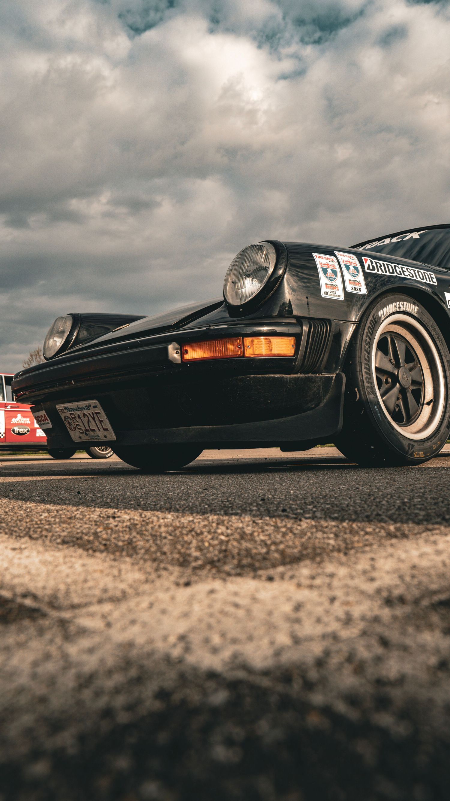 Low profile side view of vintage race cars lined up on a textured track surface.