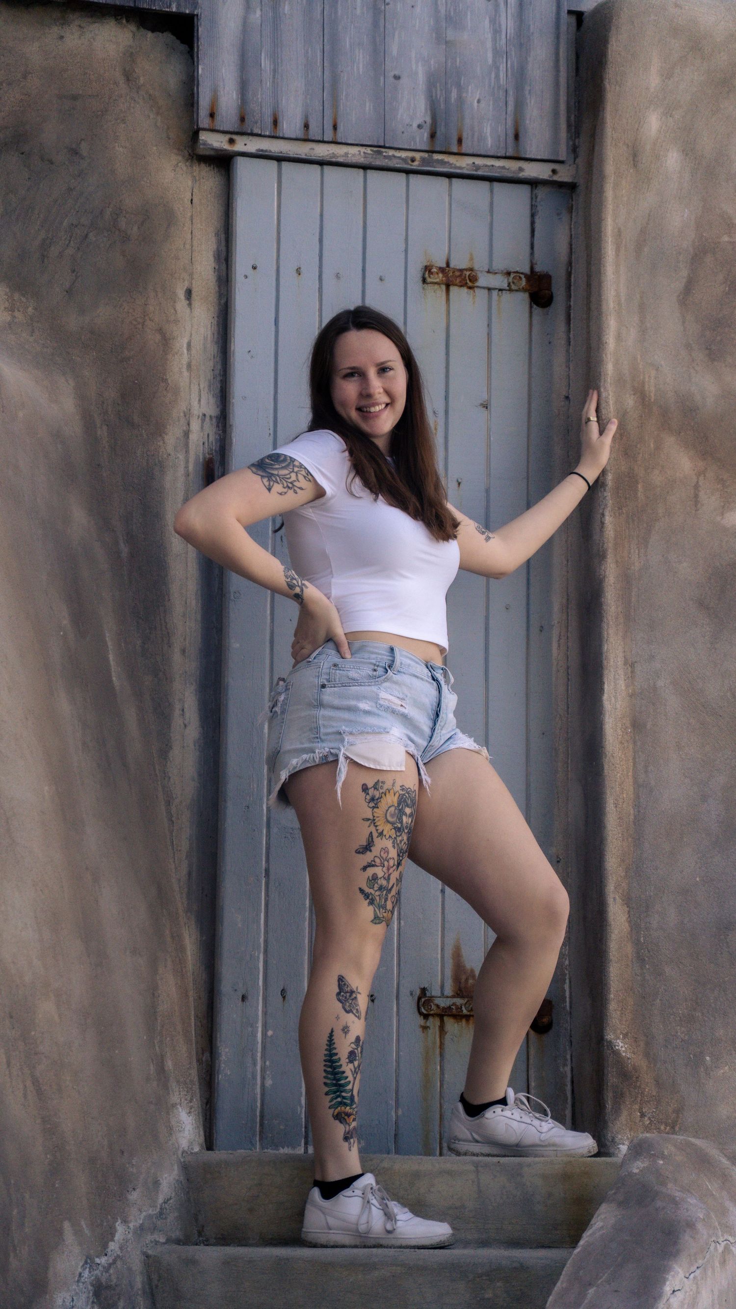 Fashion portrait on concrete steps featuring artistic tattoos and casual summer style.